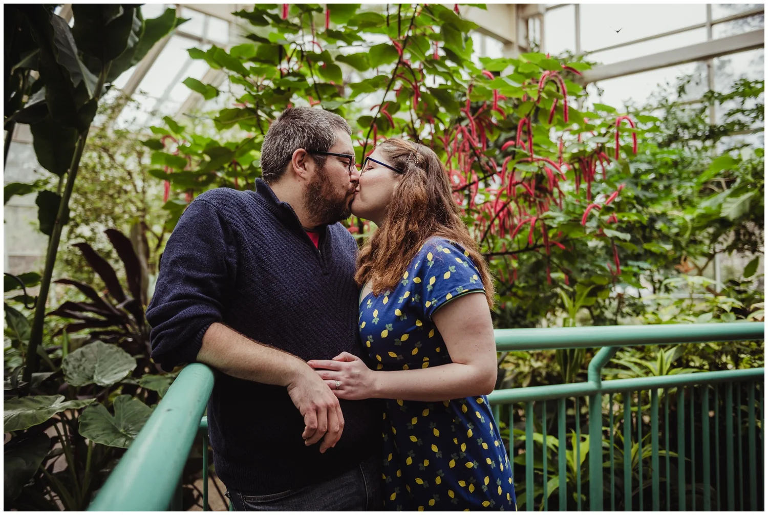 The couple steal a kiss in the Butterfly House during their engagement photo session with Rose Trail Images in Durham, NC.