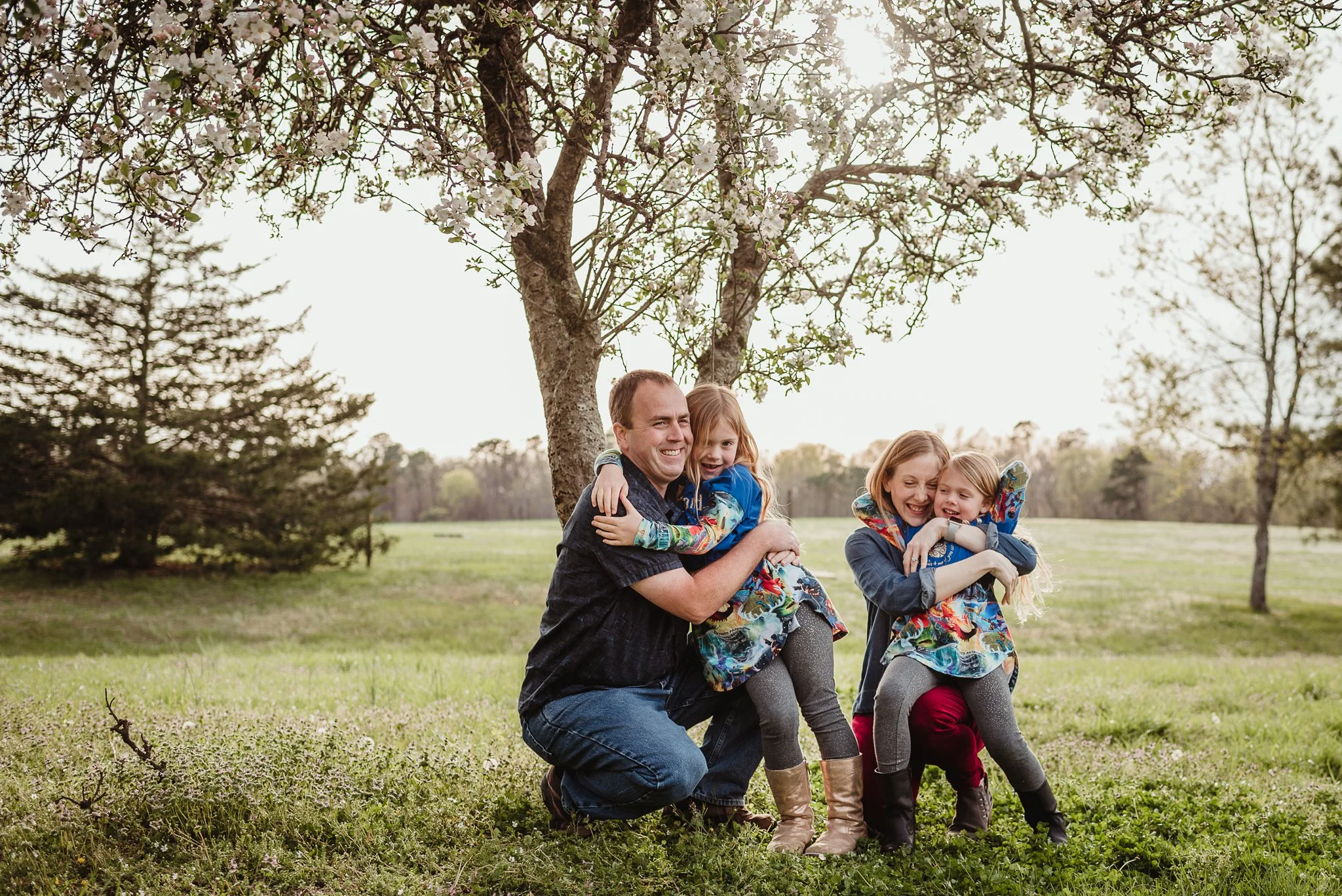The daughters hug their parents during their family photo session with Rose Trail Images in Wake Forest, North Carolina.
