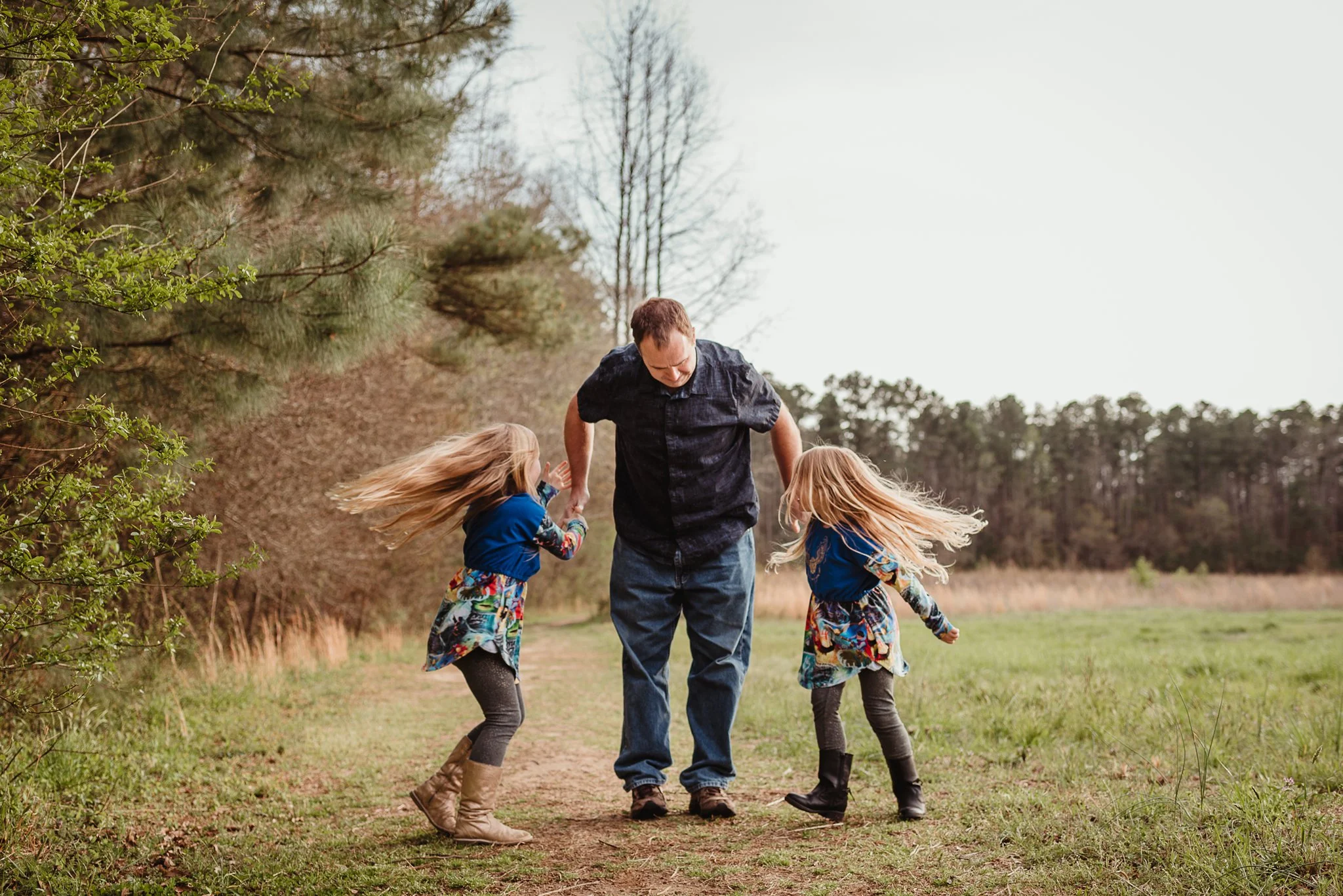 The daughters dance with their dad during their family photo session with Rose Trail Images in Wake Forest, North Carolina.