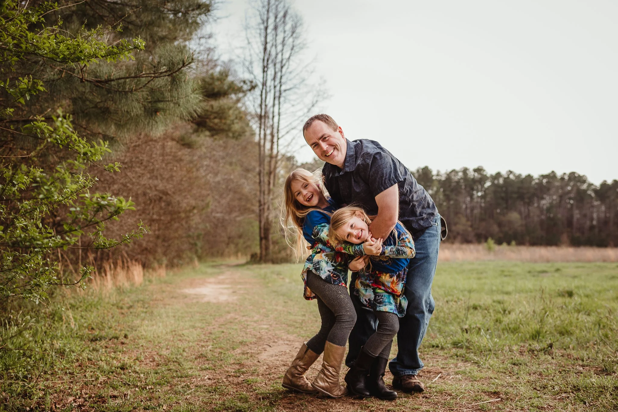The daughters snuggle with their dad during their family photo session with Rose Trail Images in Wake Forest, North Carolina.