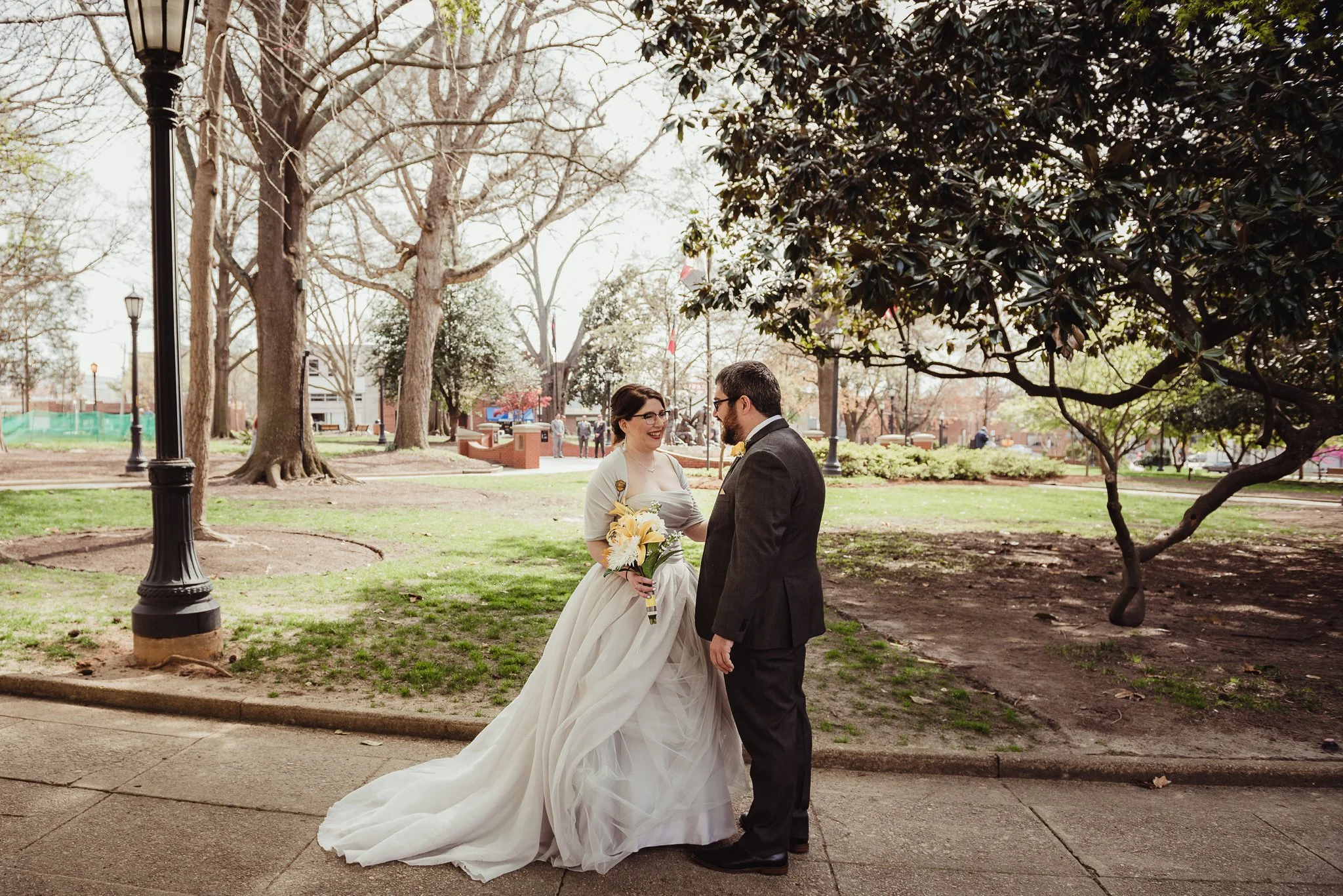 The bride and groom laugh together in the park before their wedding day in downtown Raleigh, picture by Rose Trail Images.