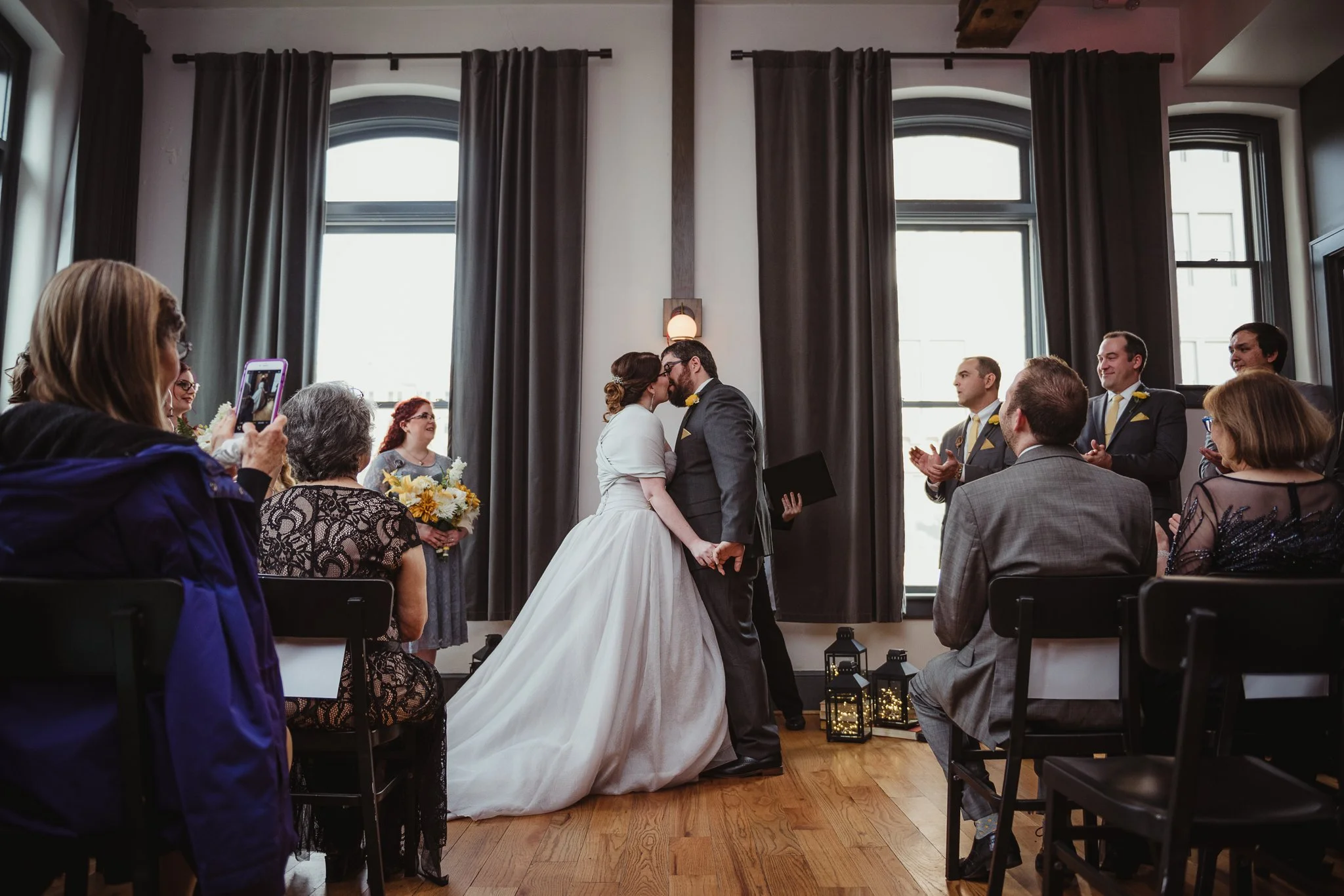 The bride and groom share their first kiss at their wedding ceremony at The Bridge Club in Raleigh, NC, picture by Rose Trail Images.