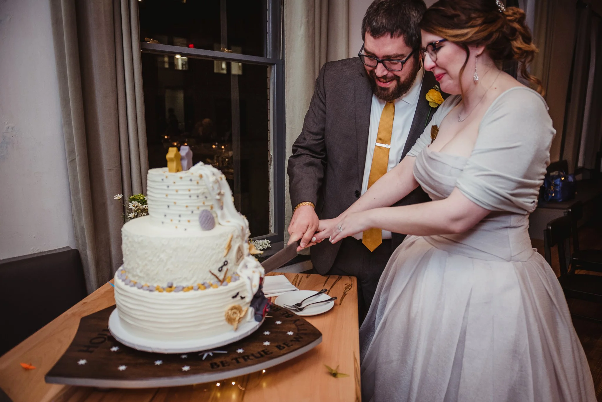 The bride and groom cut their Harry Potter/Star Wars/Lord of the Rings wedding cake at their wedding reception in Raleigh, NC, picture by Rose Trail Images.
