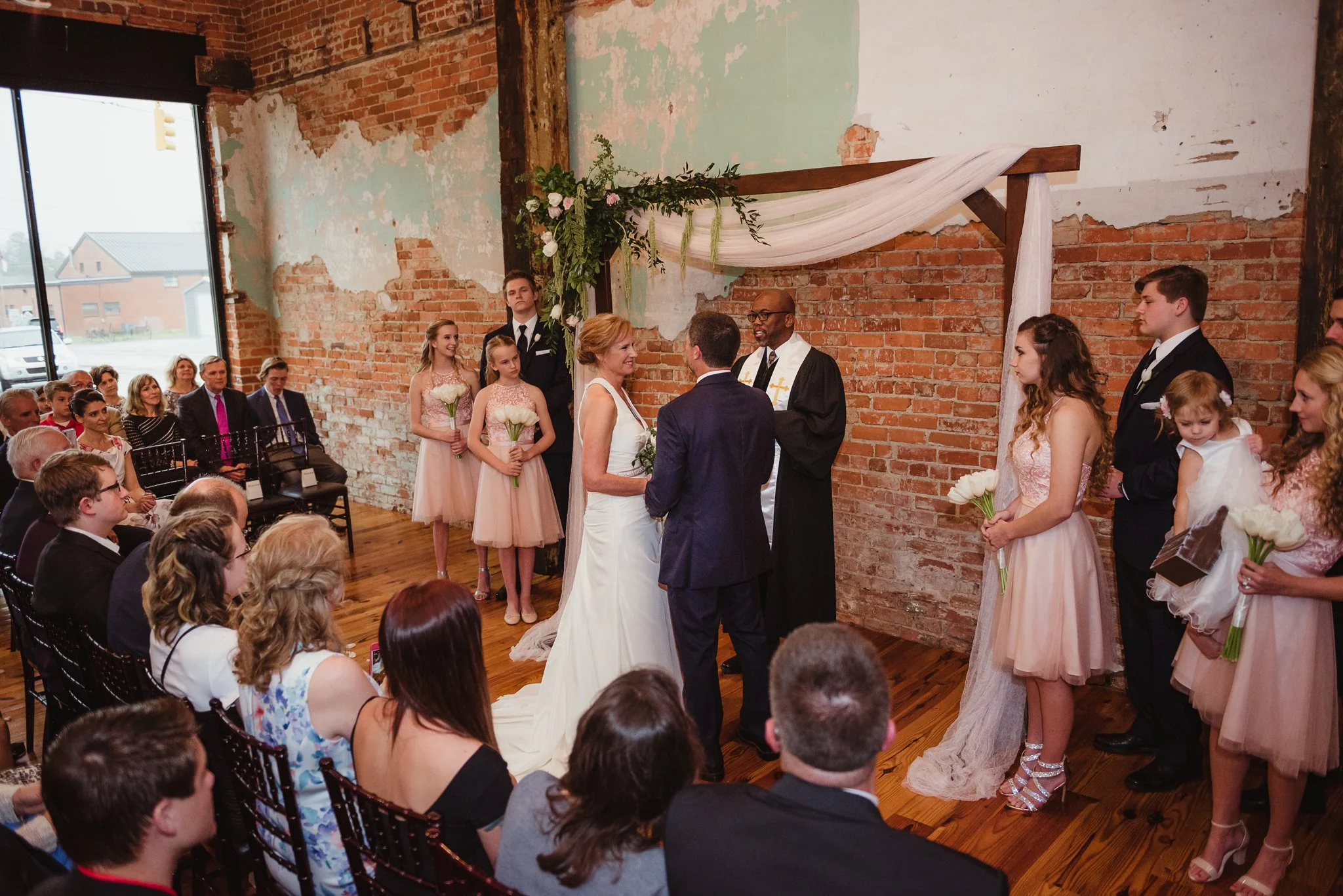 The bride and groom look at each other during their wedding ceremony at Cross and Main in Youngsville, NC, image taken by Rose Trail Images. 