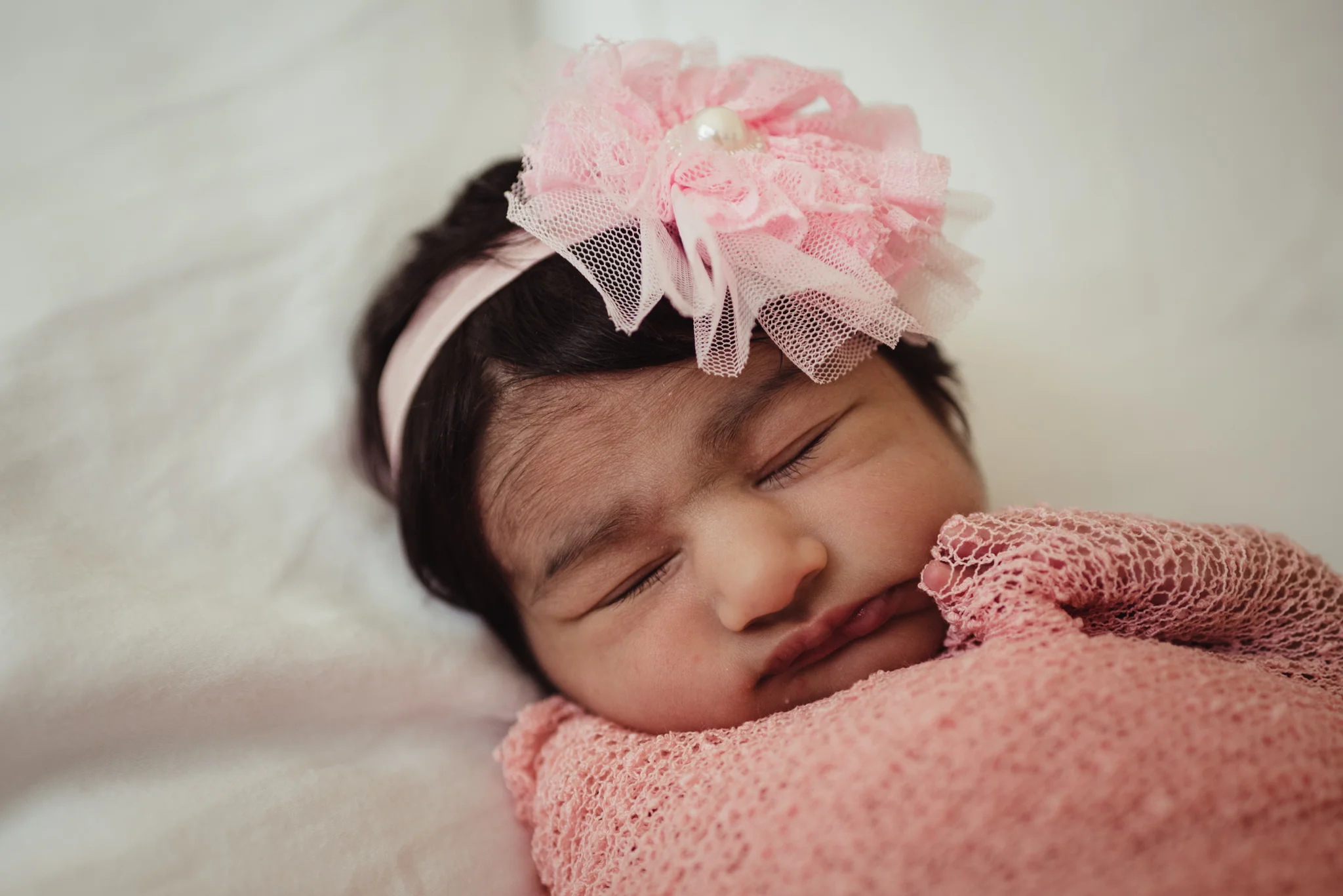  The newborn baby girl sleeps on her parents' bed during her lifestyle newborn session with Rose Trail Images in Raleigh, North Carolina. 