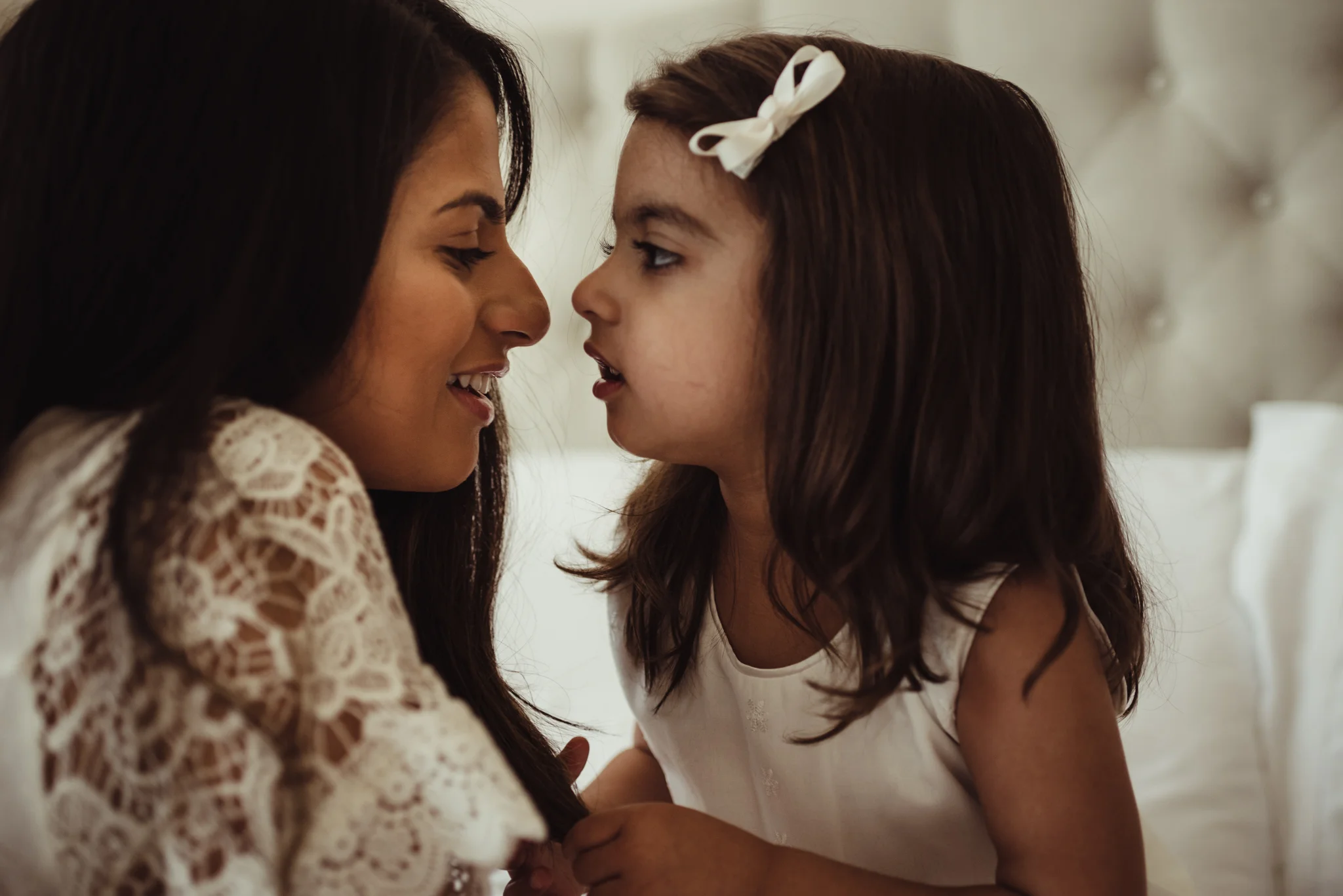 Older sister gives Mommy a kiss and a smile during their lifestyle newborn session with Rose Trail Images in Raleigh, North Carolina. 