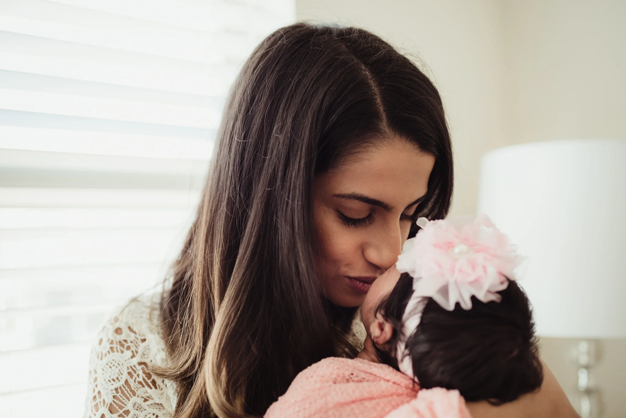 Mom kisses her newborn girl during their lifestyle newborn session with Rose Trail Images in Raleigh, North Carolina. 