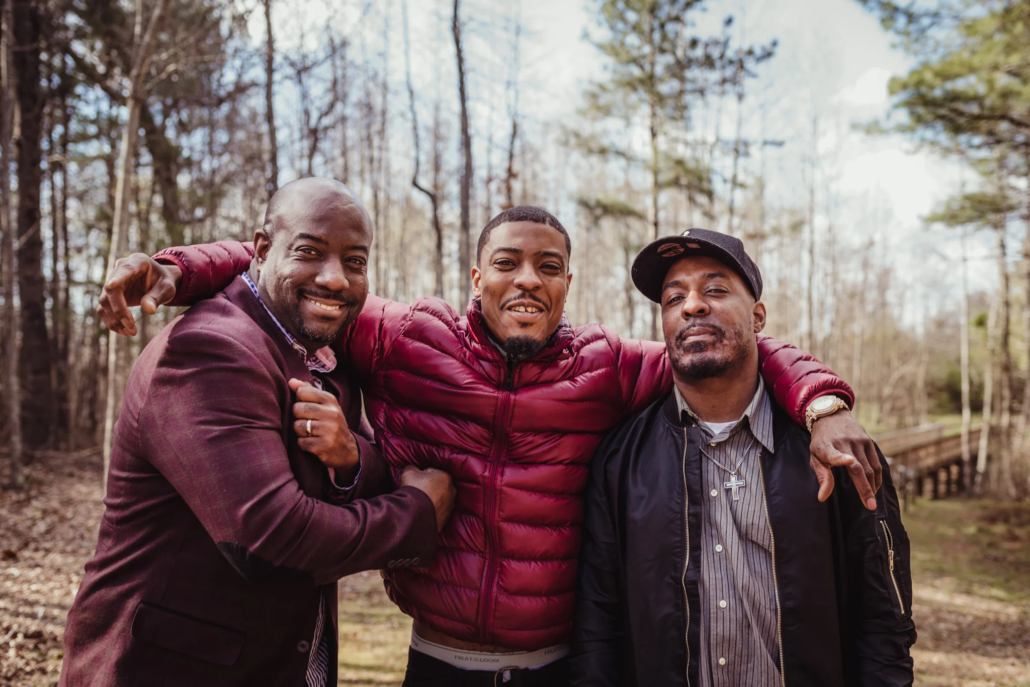 The three adult sons pose on the bridge for Rose Trail Images during their family photo session in Rolesville Main Street Park.
