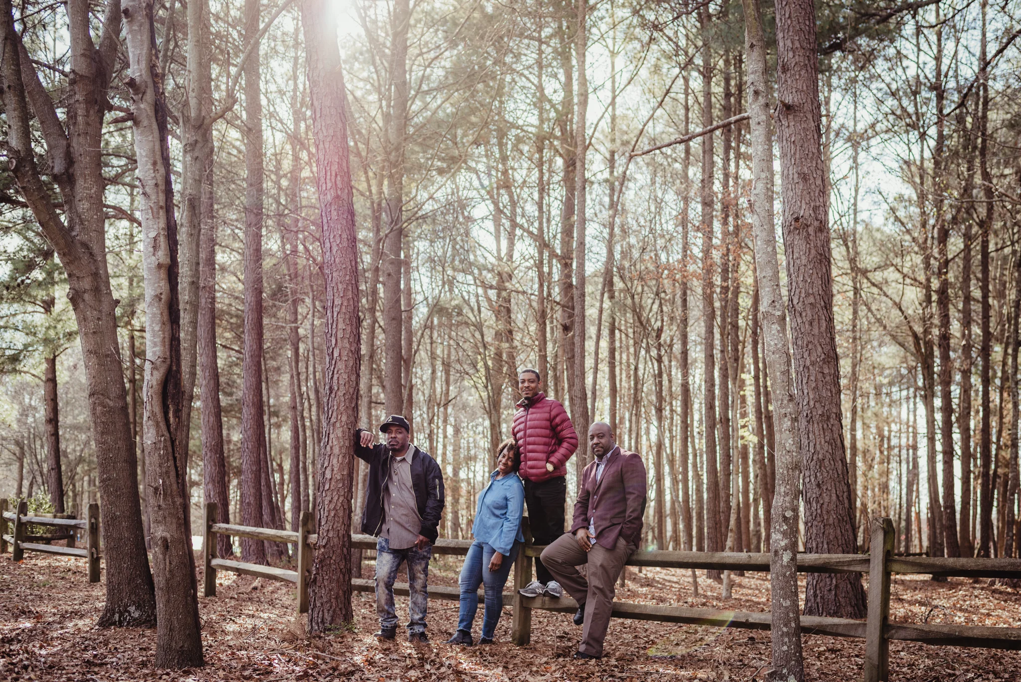 Mama and her three adult sons pose by the fence for Rose Trail Images during their family photo session in Rolesville Main Street Park.
