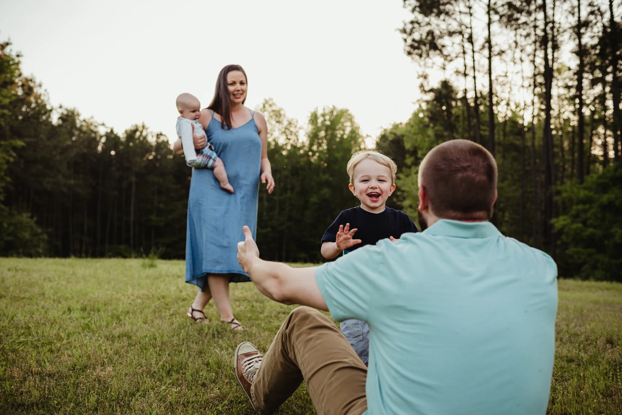 Older brother runs and tackles Daddy during their family photo session with Rose Trail Images in Rolesville, North Carolina.
