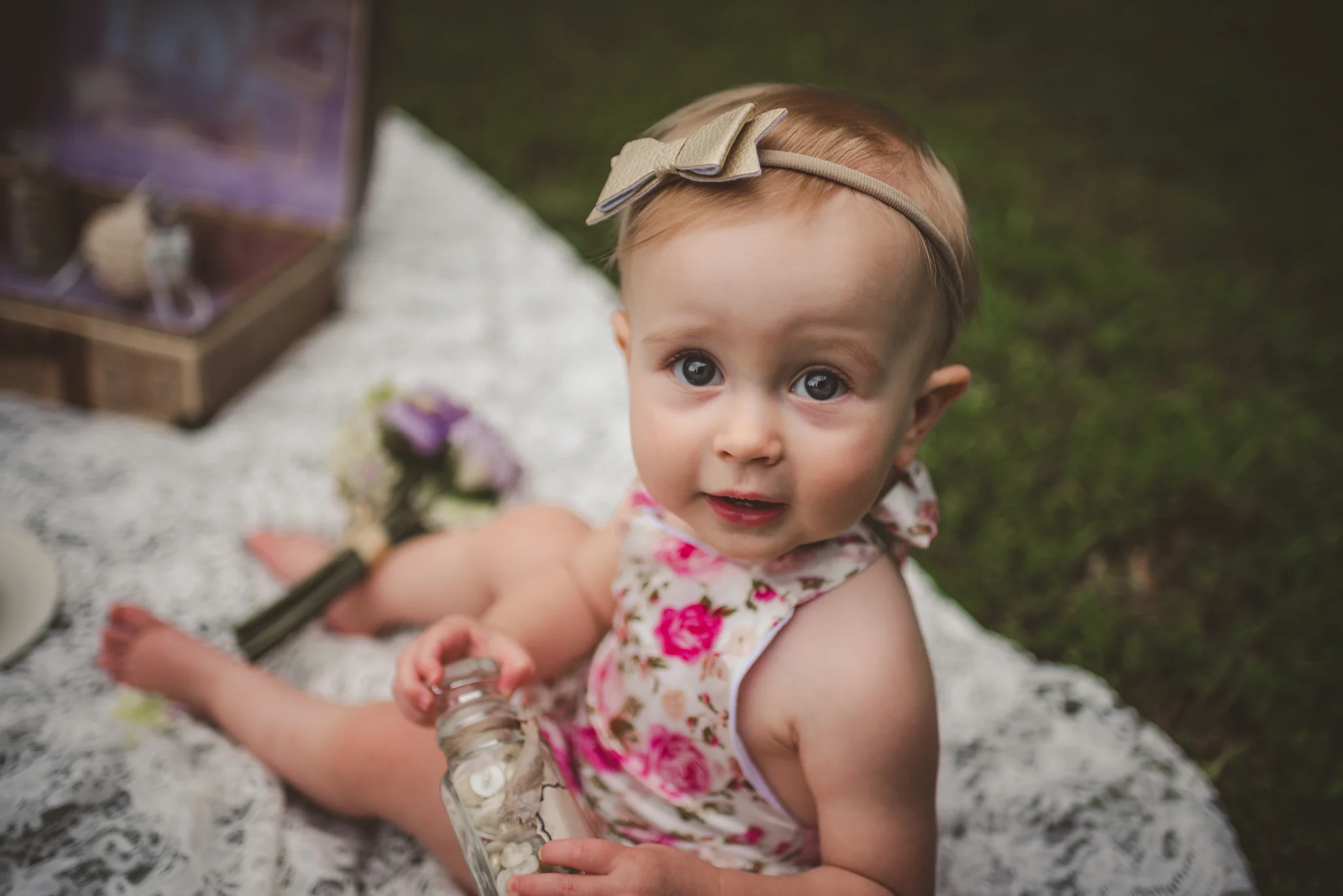 This little girl is sitting and smiling for her first birthday with vintage props from her parents wedding in Rolesville, North Carolina, image taken by Rose Trail Images.