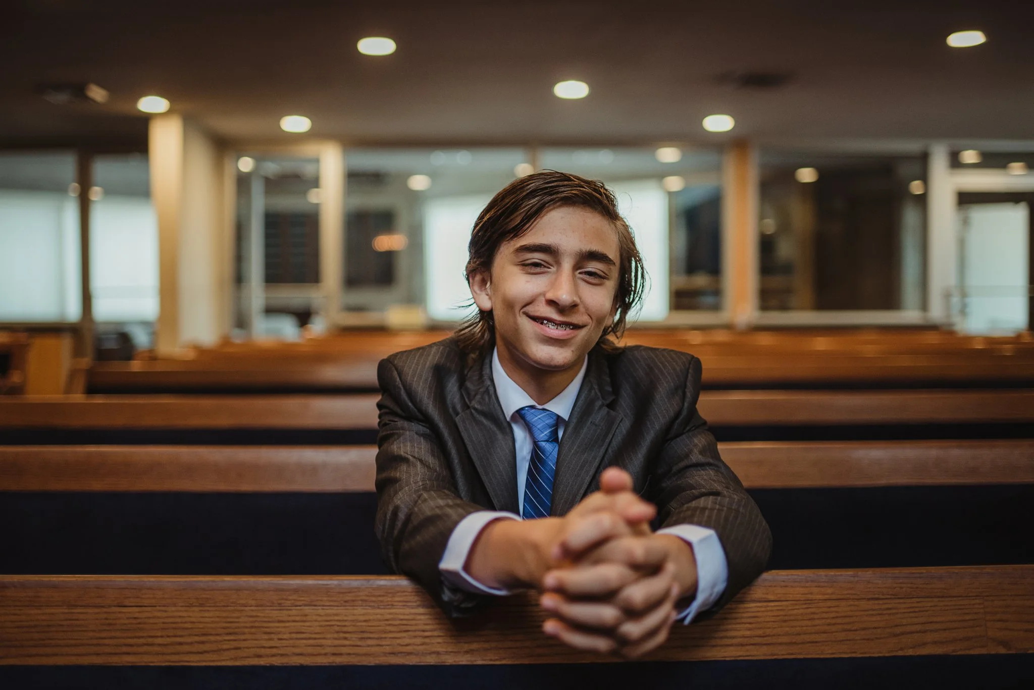 The bar mitzvah boy poses in a pew for Rose Trail Images at Temple Beth Or in Raleigh, North Carolina.
