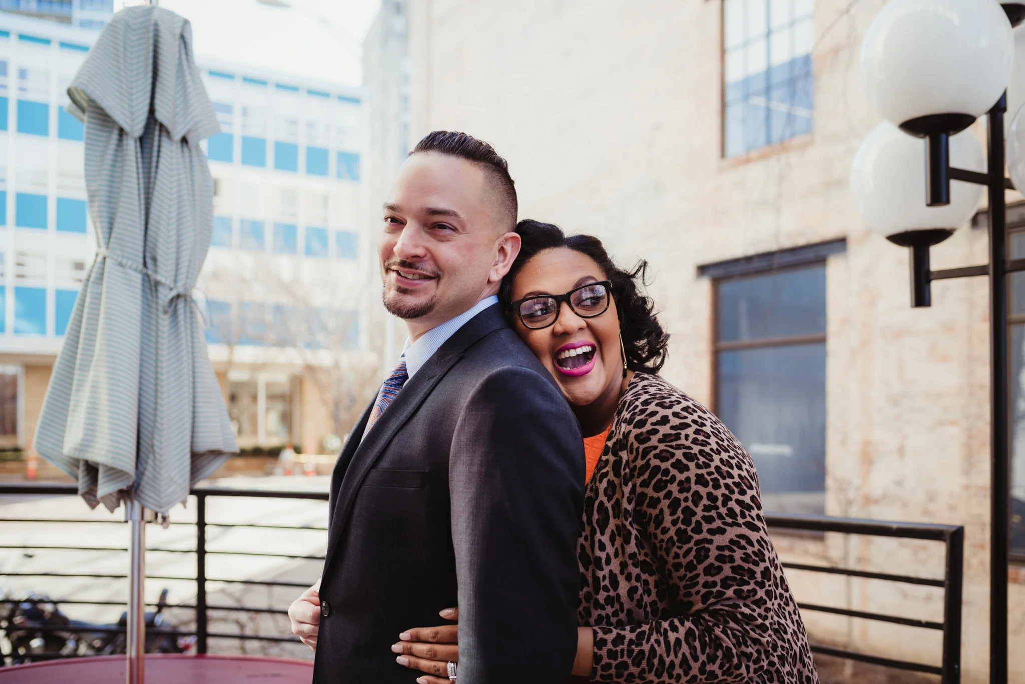 The wife gives her husband a big hug outside of The Durham Hotel in Durham, North Carolina, image by Rose Trail Images.