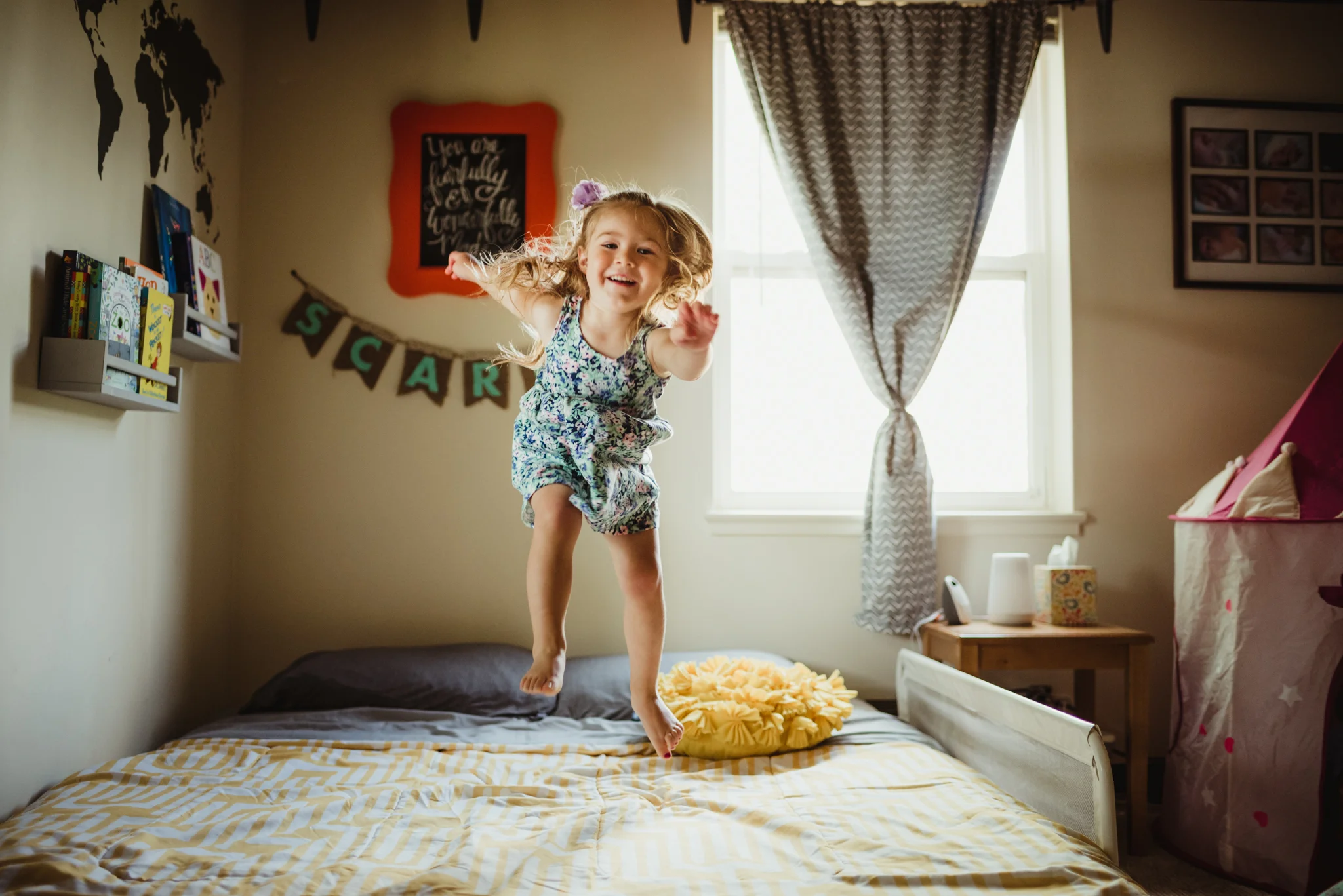 The little girl jumps up and down on her bed during their lifestyle session at home in Wake Forest with Rose Trail Images.