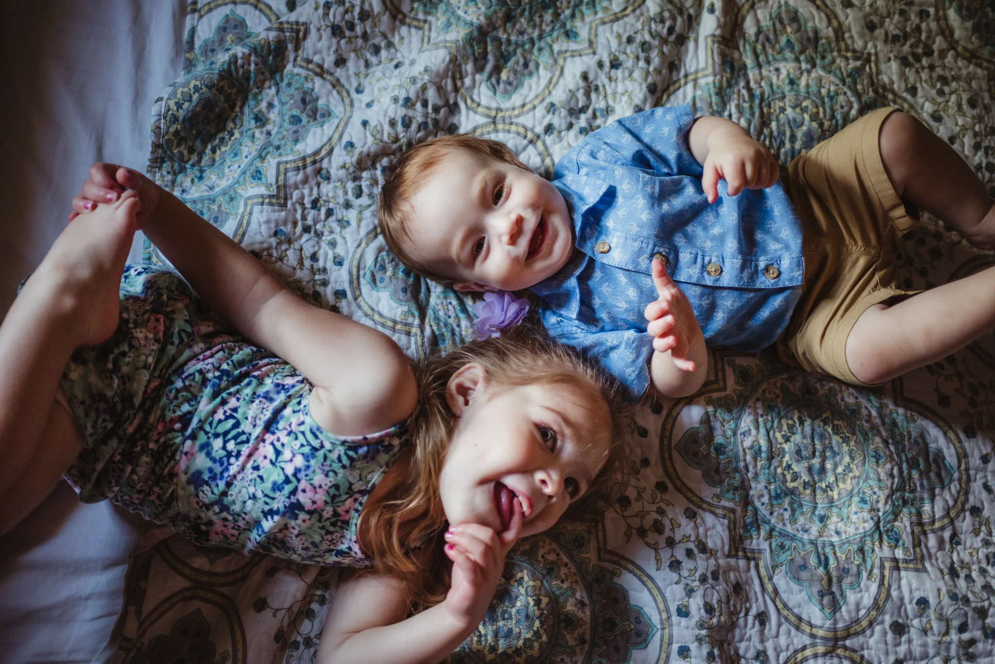The kids lay together on their parents' bed during their lifestyle session at home in Wake Forest with Rose Trail Images.