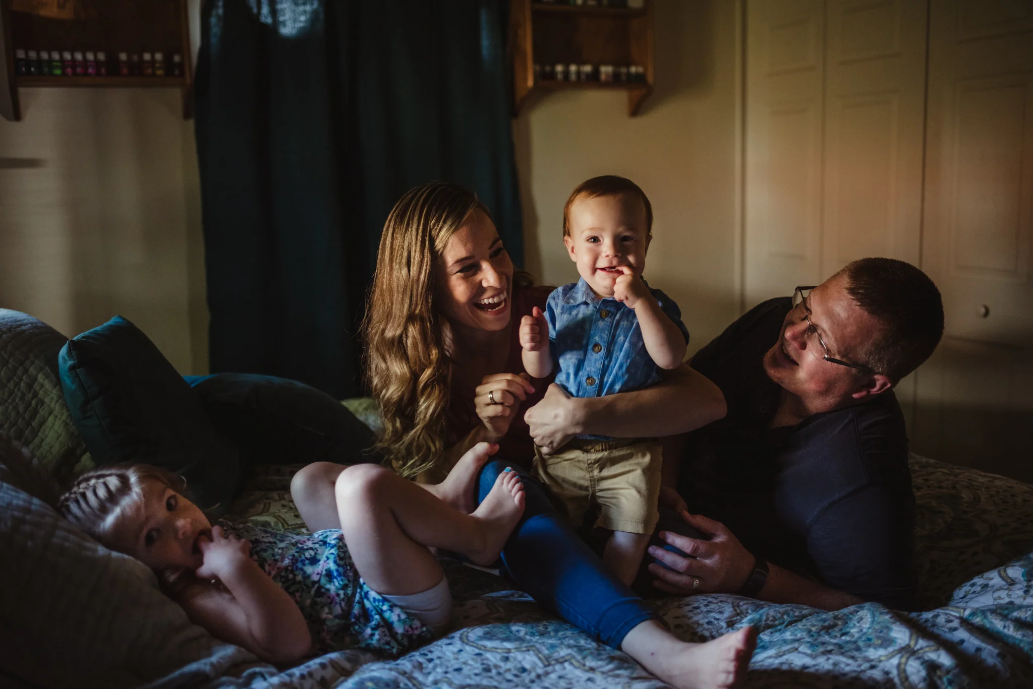The family plays together on the parents' bed during their lifestyle session at home in Wake Forest with Rose Trail Images.