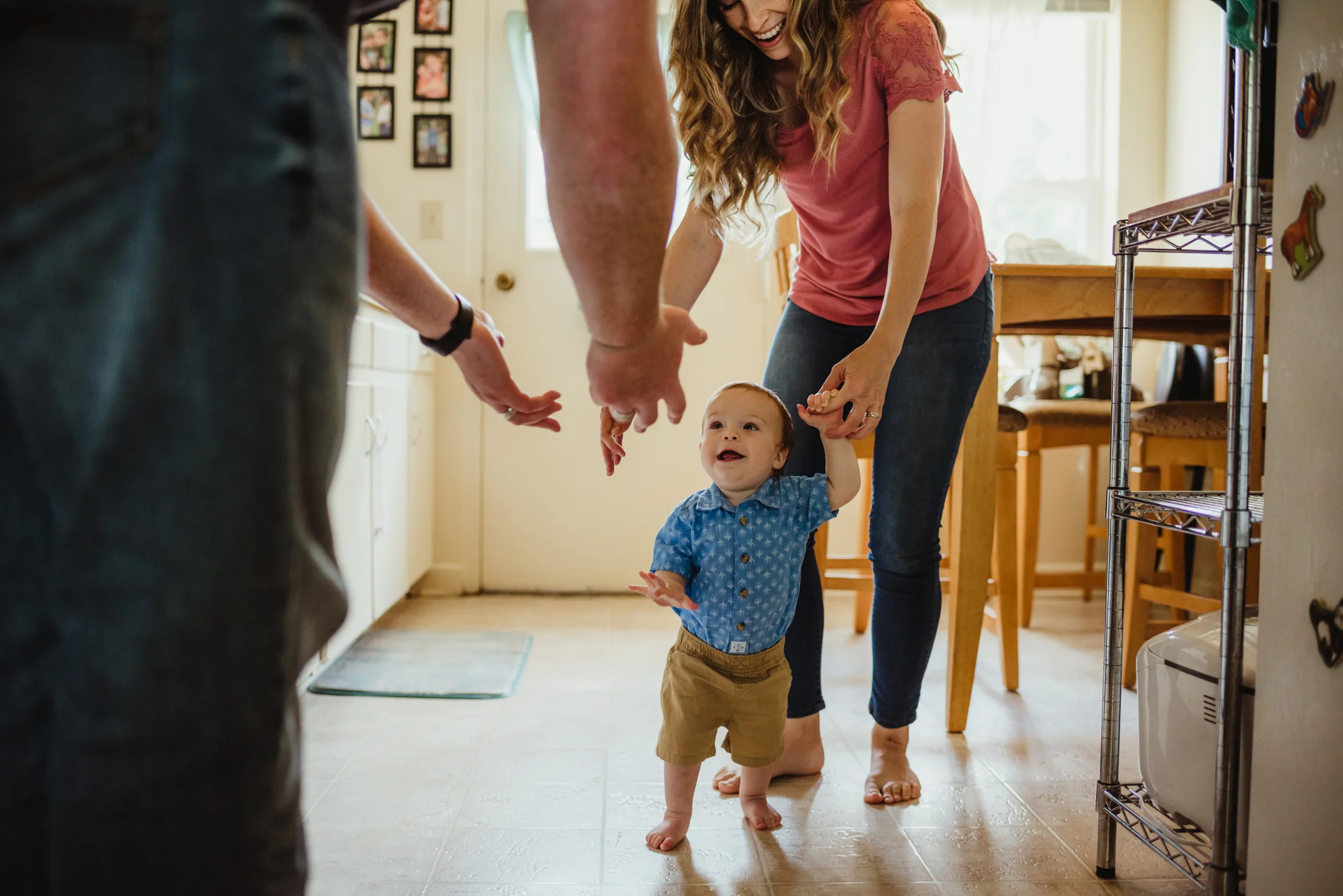The baby tries to take his first steps in the kitchen during their lifestyle session at home in Wake Forest with Rose Trail Images.