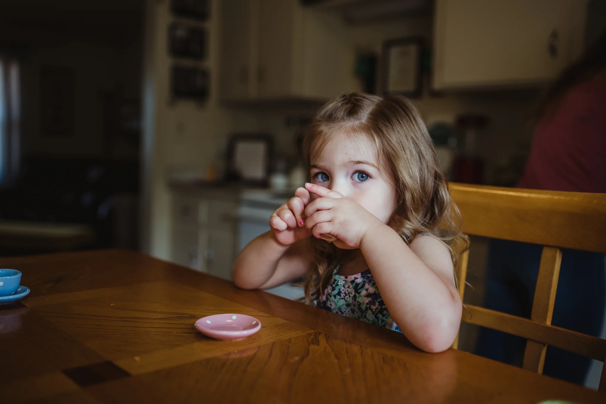 The little girl sips her tea in the kitchen during their lifestyle session at home in Wake Forest with Rose Trail Images.