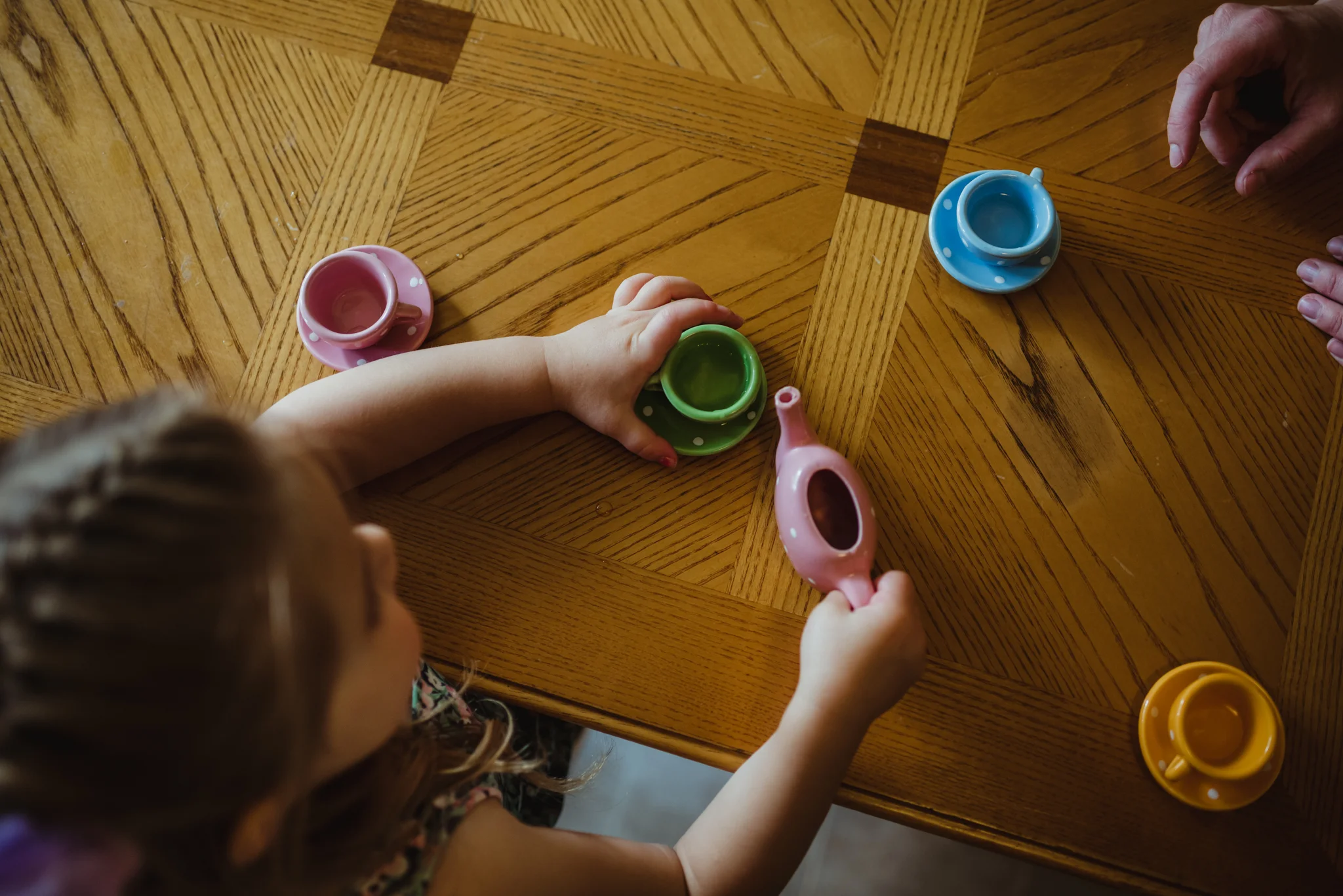 The little girl pours her tea for tea time in the kitchen during their lifestyle session at home in Wake Forest with Rose Trail Images.