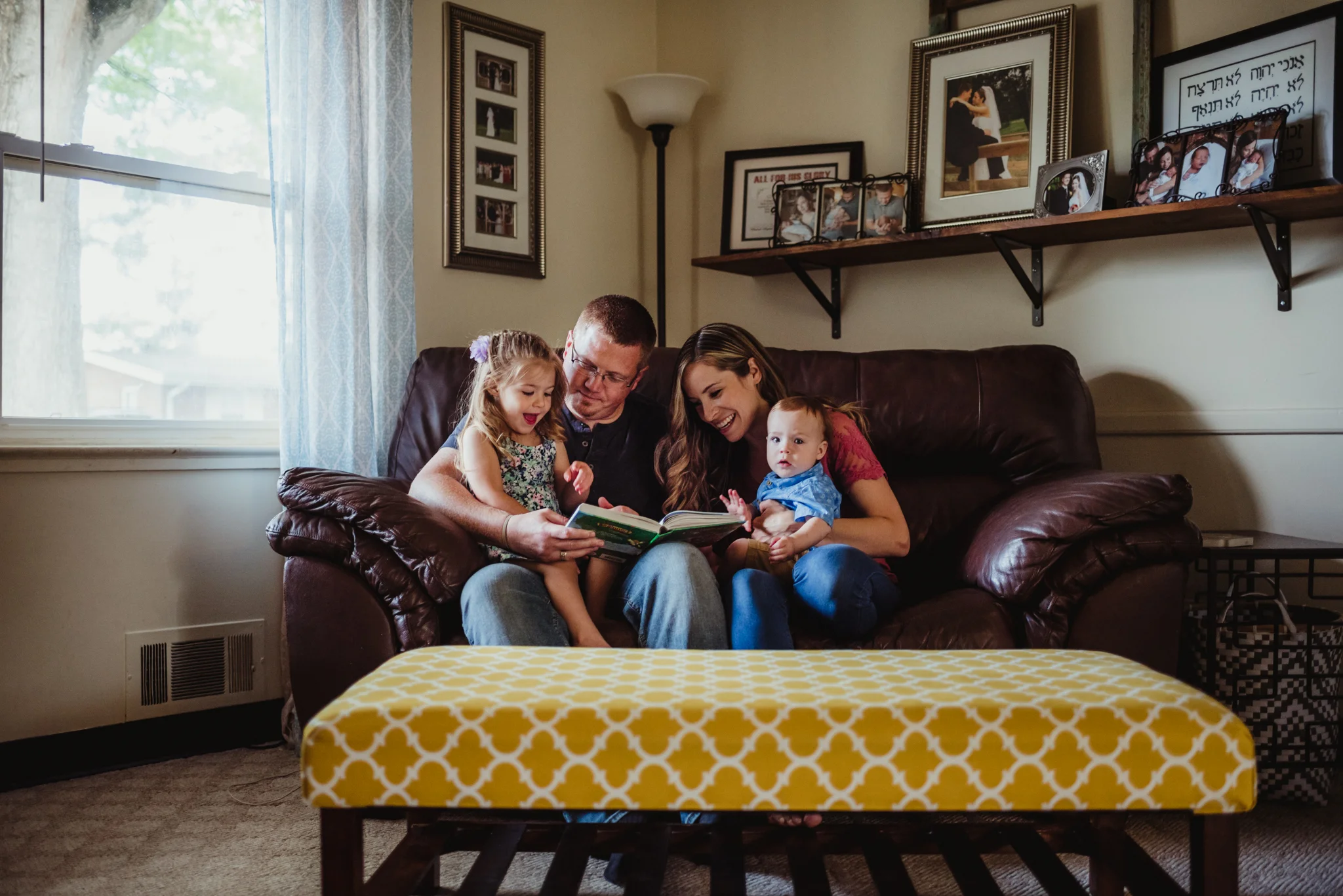 The family has story time together on the couch in the living room during their lifestyle session at home in Wake Forest with Rose Trail Images.