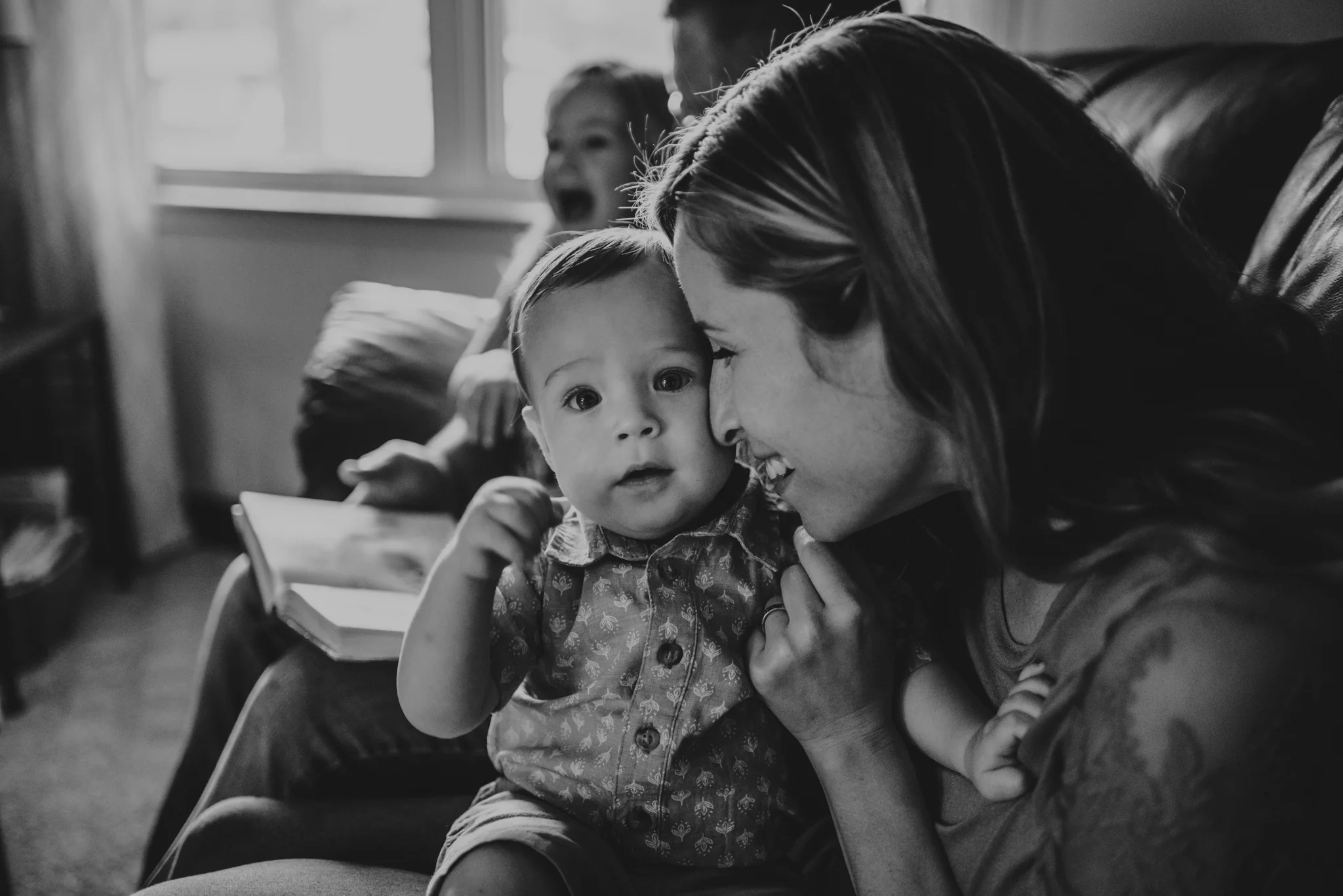 Mommy snuggles baby during story time together on the couch during their lifestyle session at home in Wake Forest with Rose Trail Images.