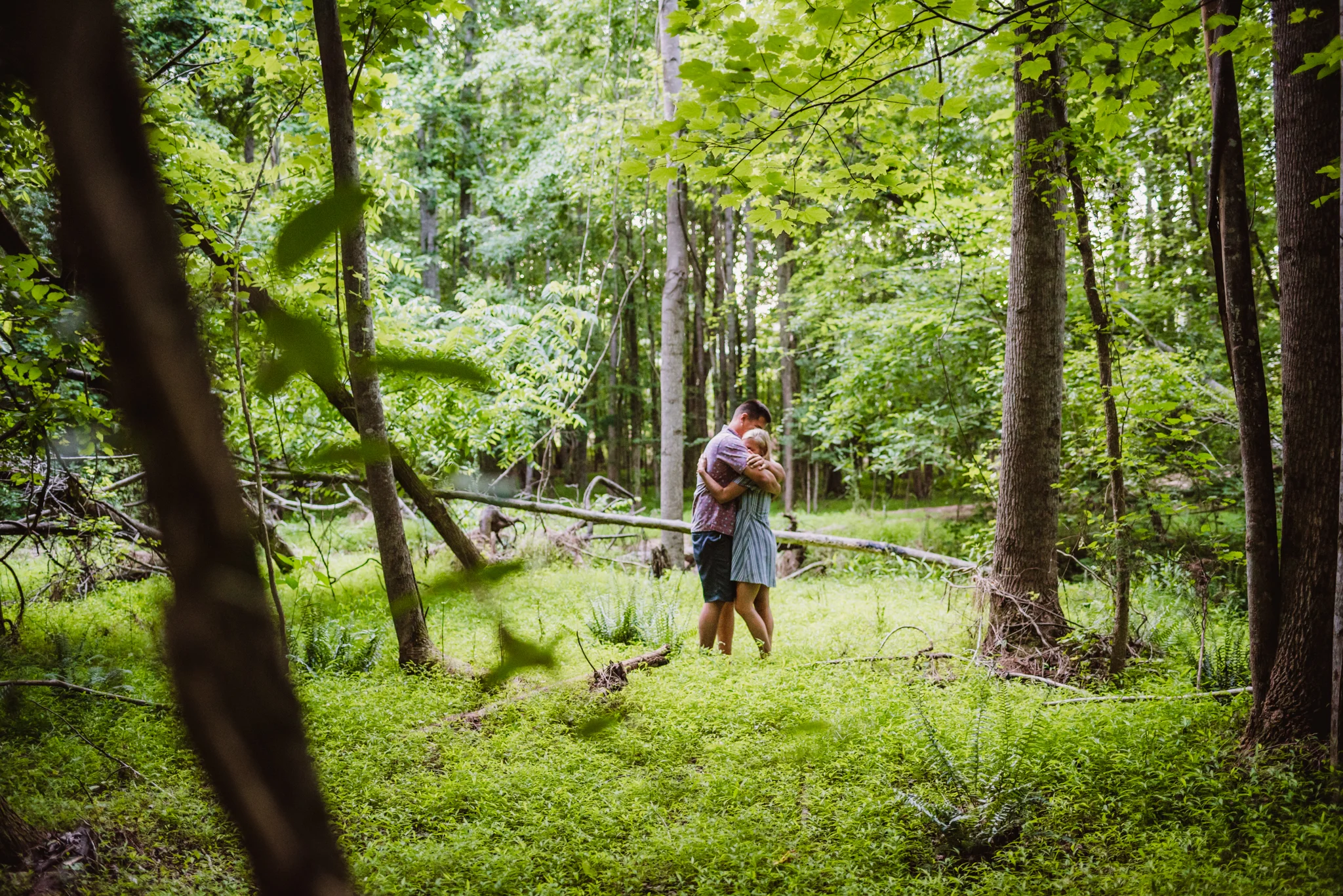 Kristin and Drew hugged in the woods during their engagement shoot in Raleigh with Rose Trail Images.