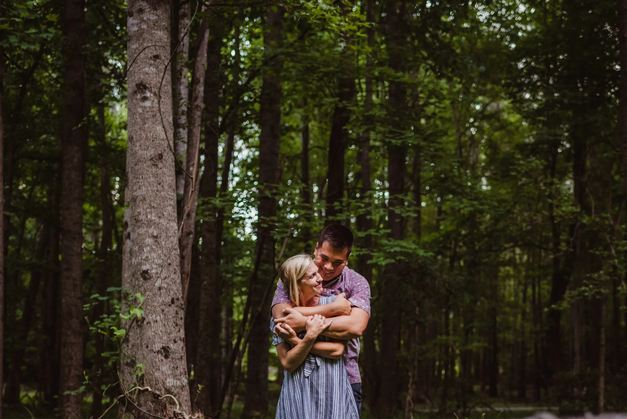 Kristin and Drew hugged each other in the woods during their engagement shoot in Raleigh with Rose Trail Images.