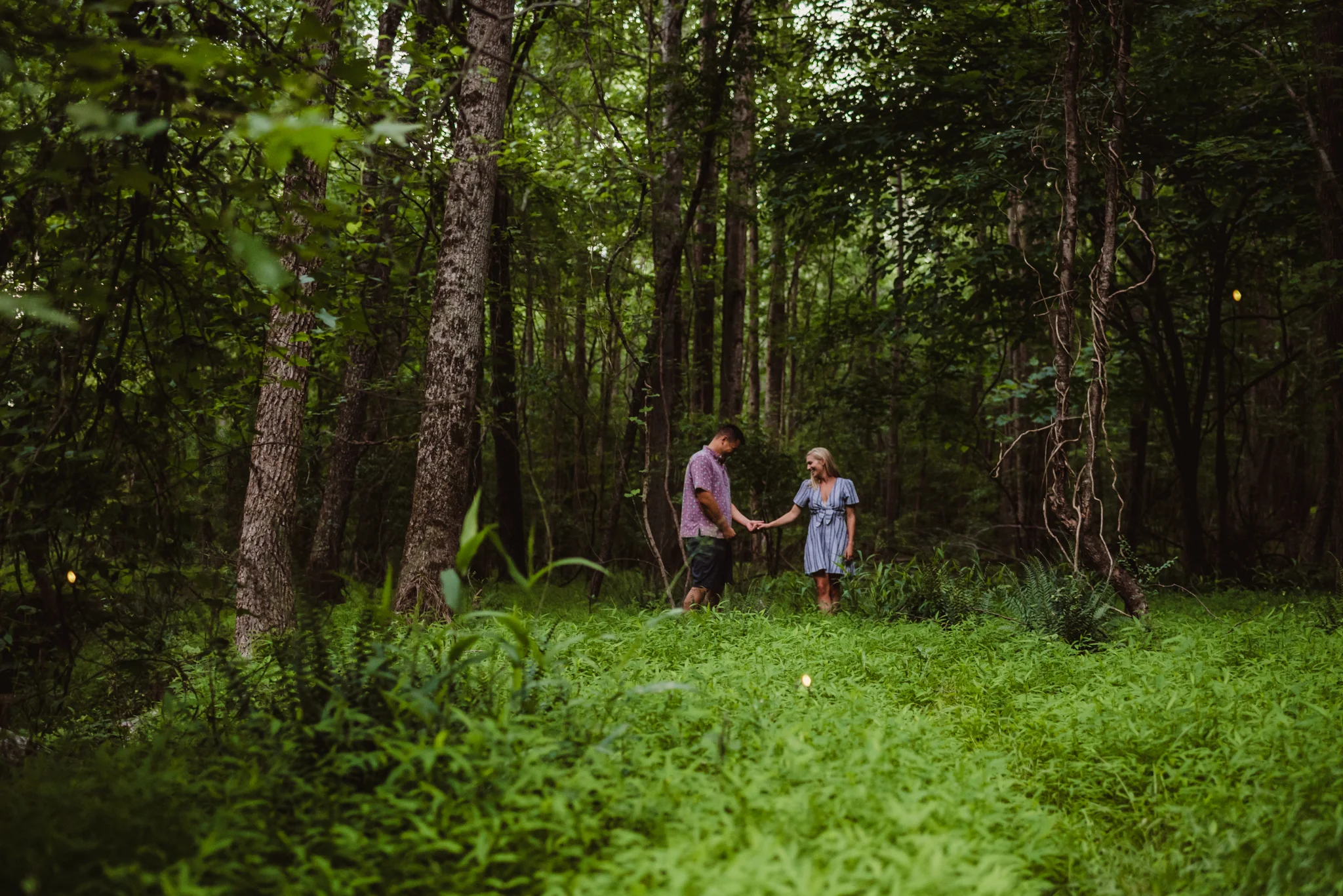 Kristin and Drew held hands in the woods during their engagement shoot in Raleigh with Rose Trail Images.