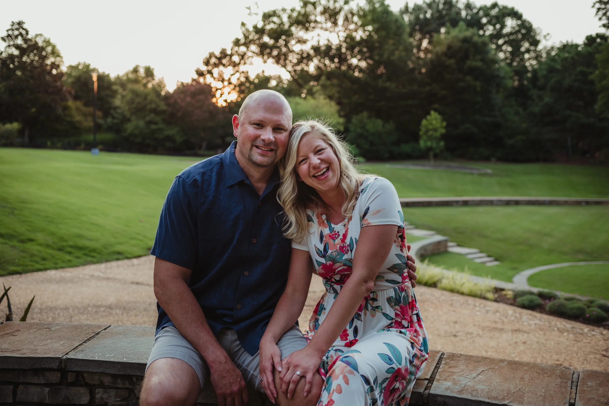 The bride and groom sit together and hold hands during their engagement session at Fred Fletcher Park in Raleigh, North Carolina with Rose Trail Images.