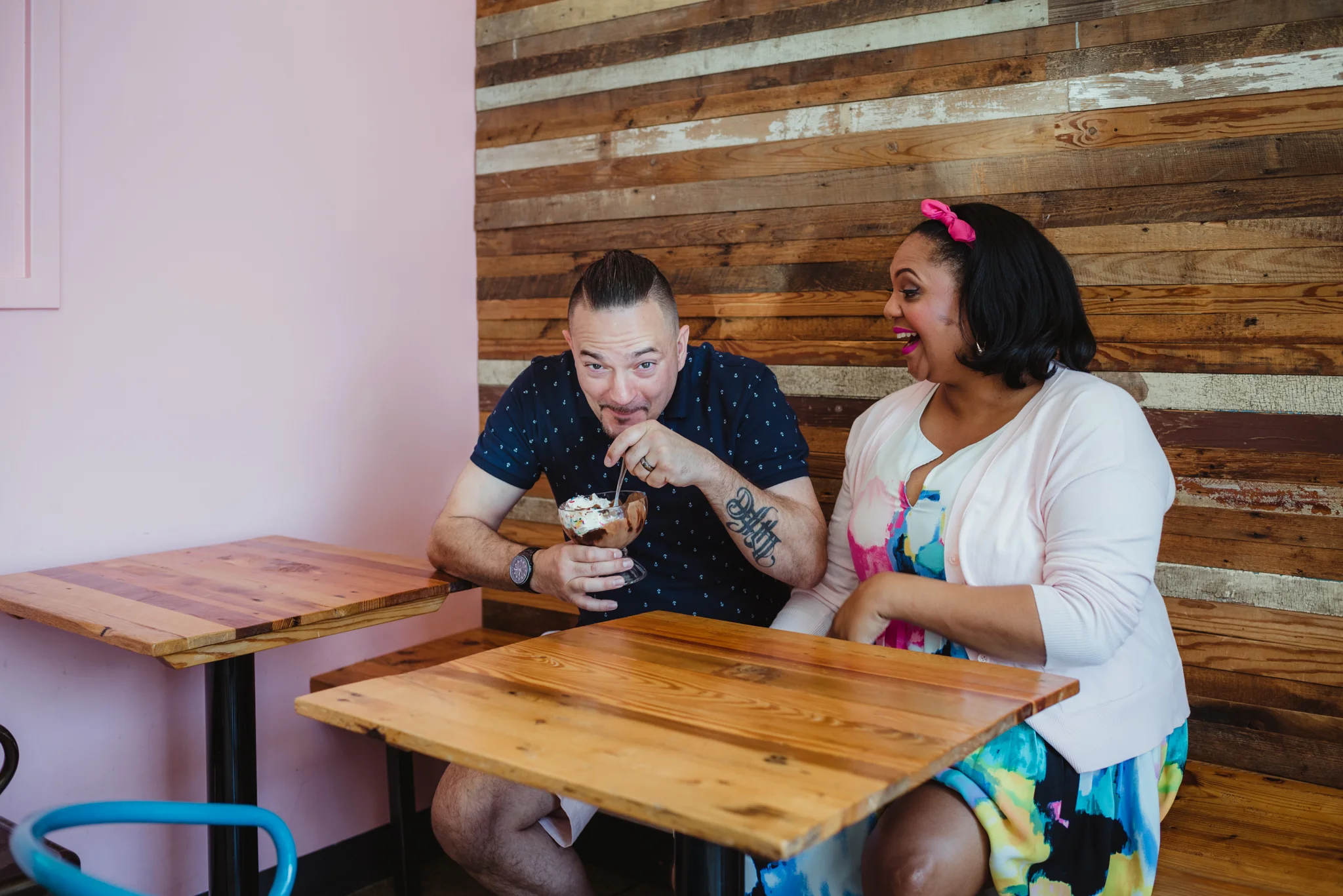 The dad to be steals the ice cream from the mom at The Parlour in Durham during their baby announcement photo session with Rose Trail Images.