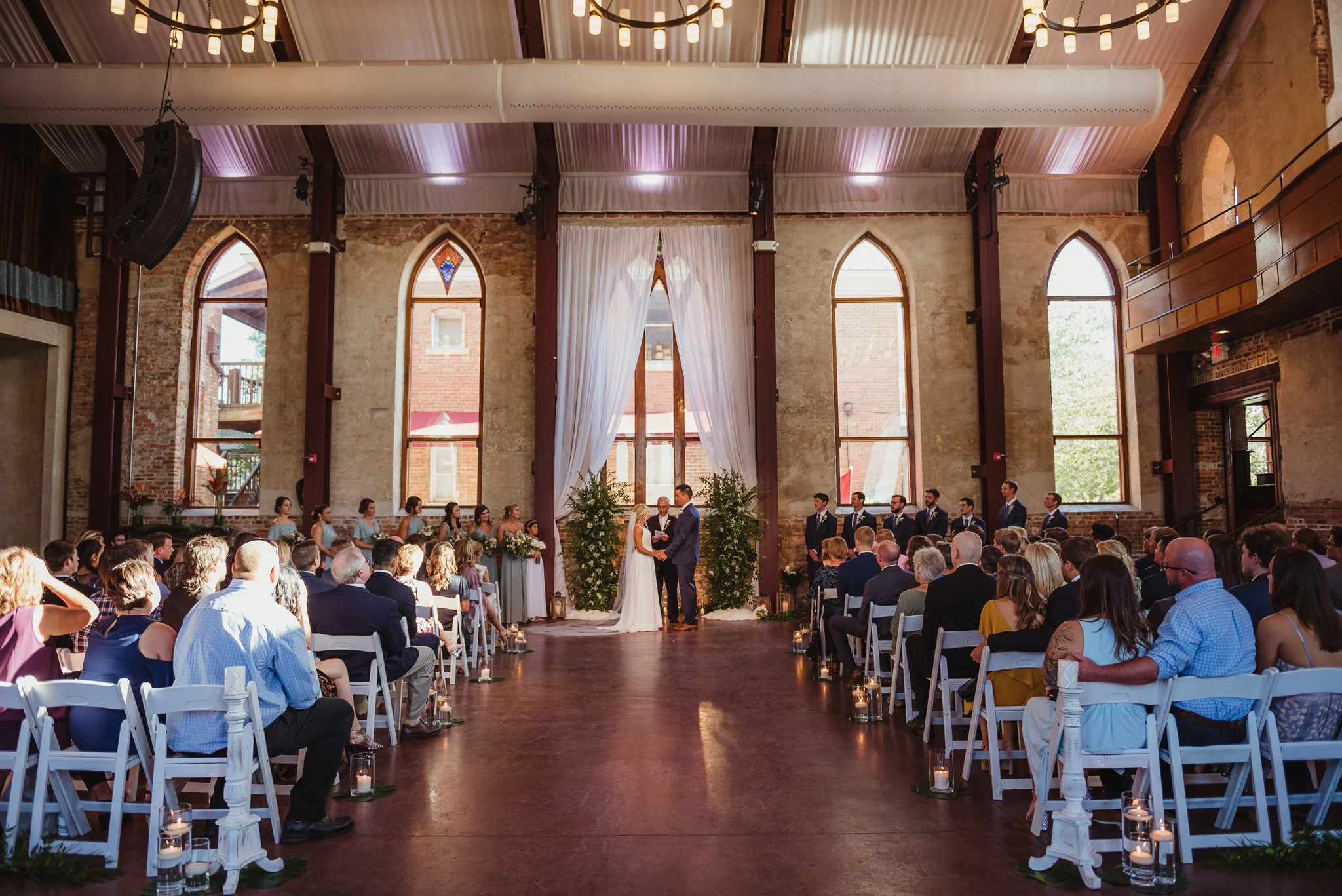 The bride and groom hold hands during their wedding ceremony at the Brooklyn Arts Center in Wilmington, NC, photos by Rose Trail Images.