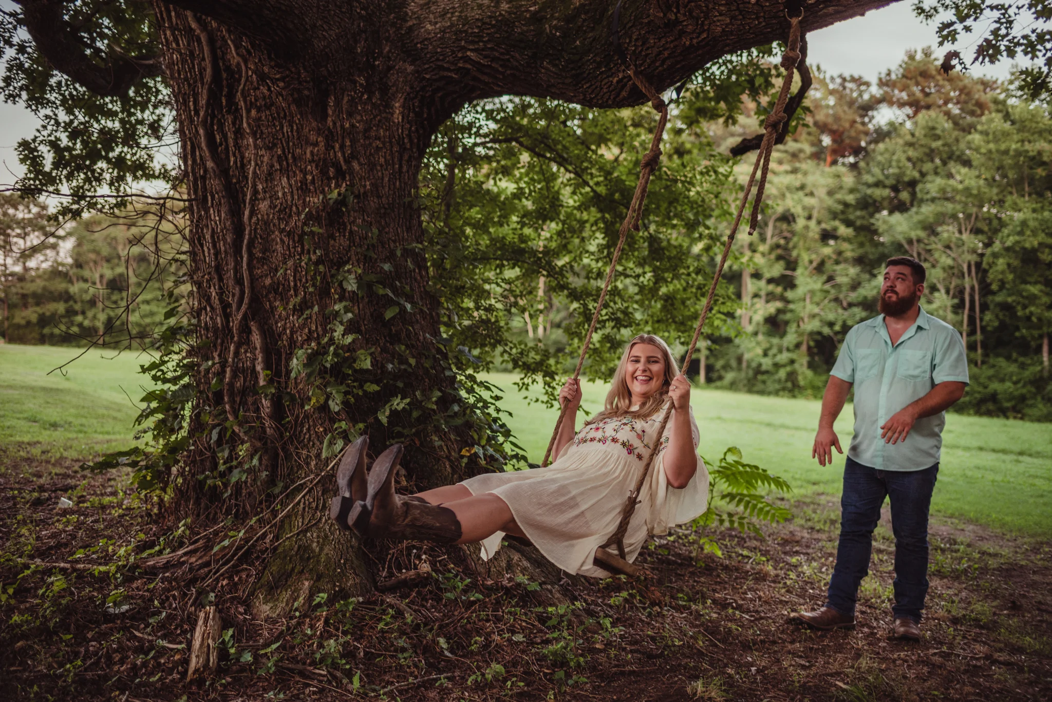 The future bride and groom play on the swings at the Warren Estate during sunset for their engagement pictures with Rose Trail Images.