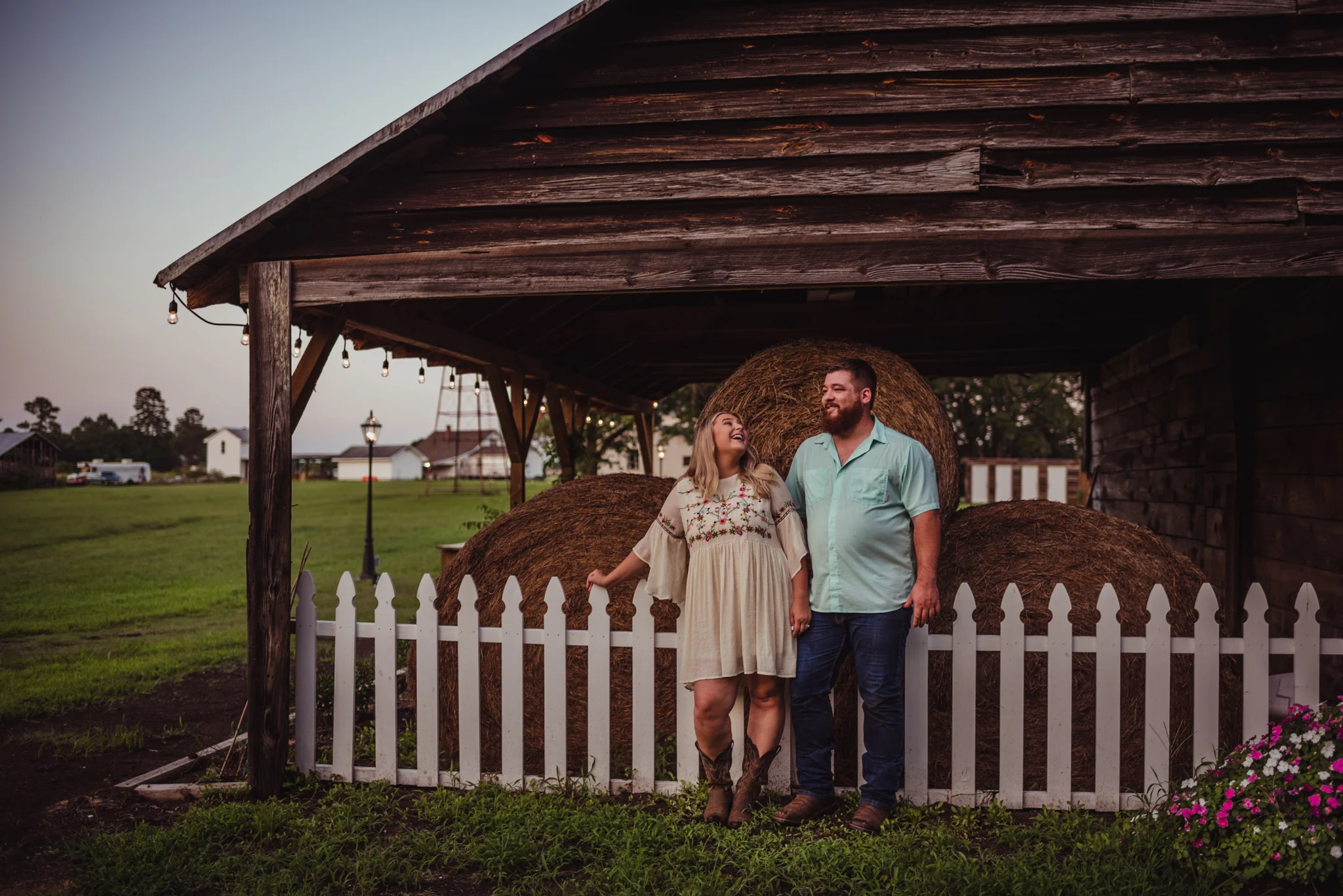 The future bride and groom hang out by the hay bales during sunset for their engagement pictures at The Warren Estate with Rose Trail Images.