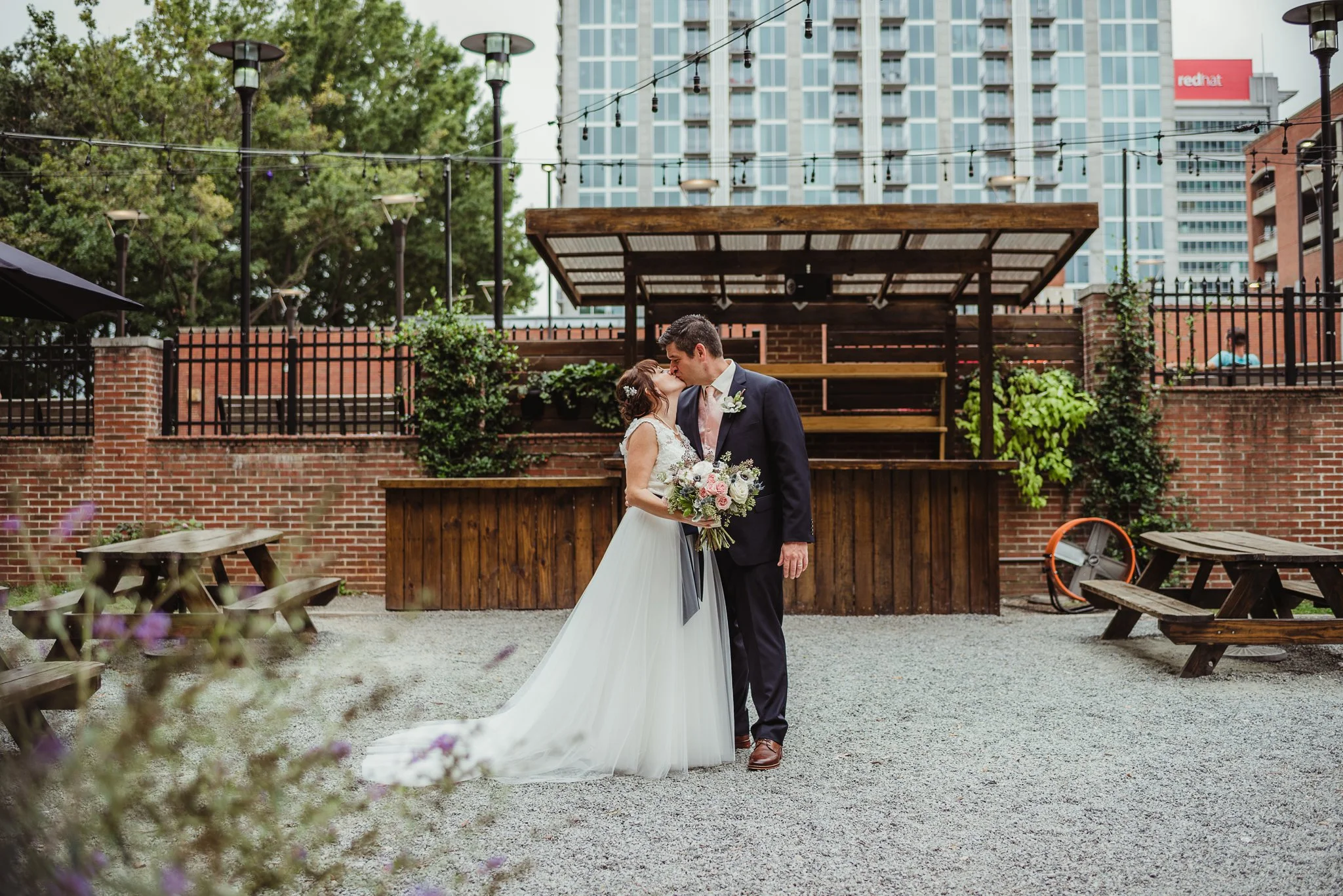 The bride and groom kiss on the patio after their wedding ceremony at Caffe Luna in downtown Raleigh, NC, photo by Rose Trail Images.