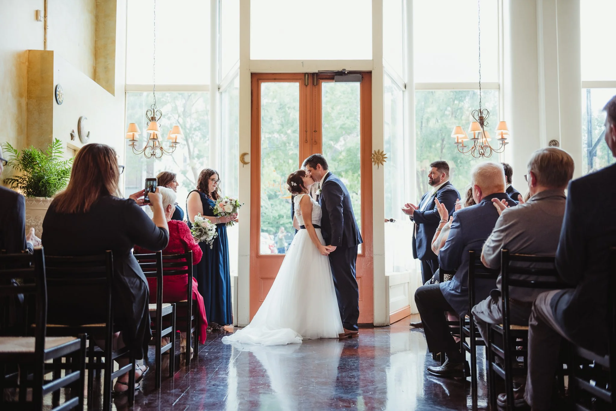 The bride and groom exchanged their first kiss as husband and wife during their wedding ceremony, pictures taken by Rose Trail Images at Caffe Luna in Raleigh, NC.