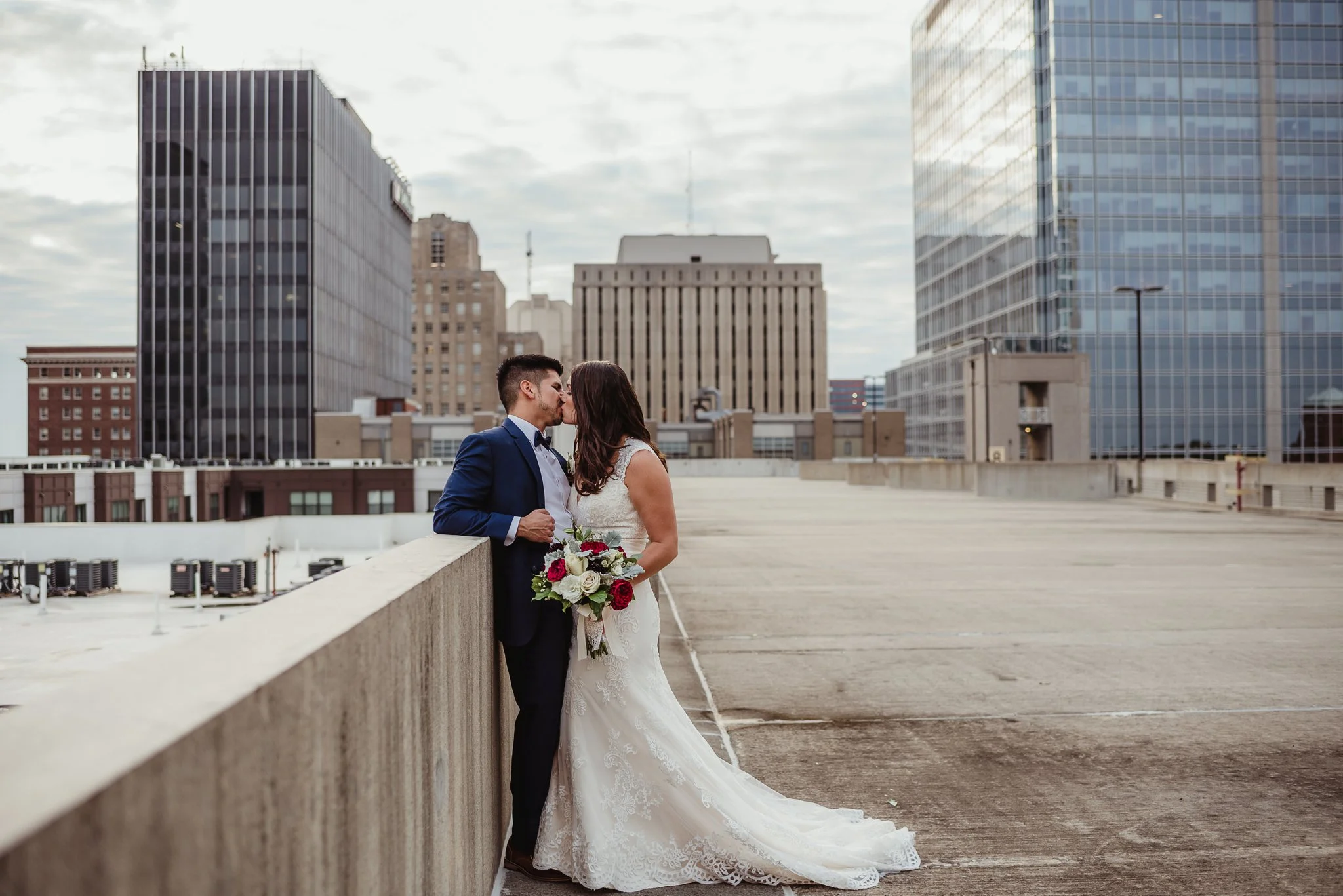 The bride and groom kiss on a rooftop after their wedding ceremony in downtown Raleigh, photo by Rose Trail Images.