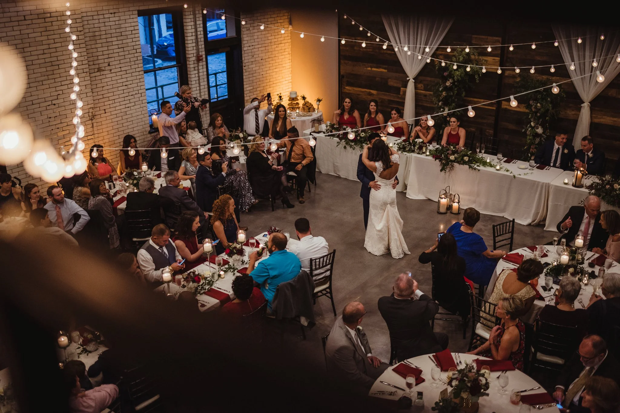 An aerial view of the bride and groom dancing their first dance together at their wedding reception at Market Hall in downtown Raleigh, photos by Rose Trail Images.