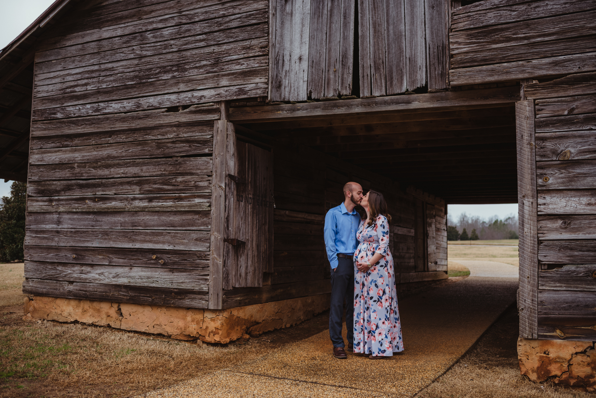 The parents to be kiss under the old barn, picture taken by Rose Trail Images at Joyner Park in Wake Forest, NC.