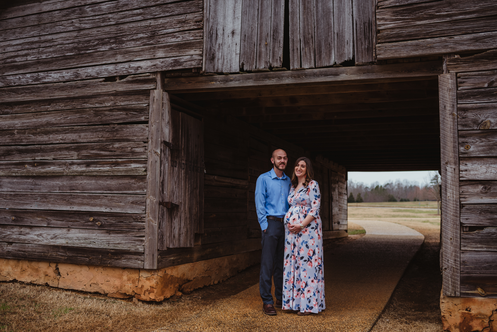 The parents to be stand under the old barn, picture taken by Rose Trail Images at Joyner Park in Wake Forest, NC.