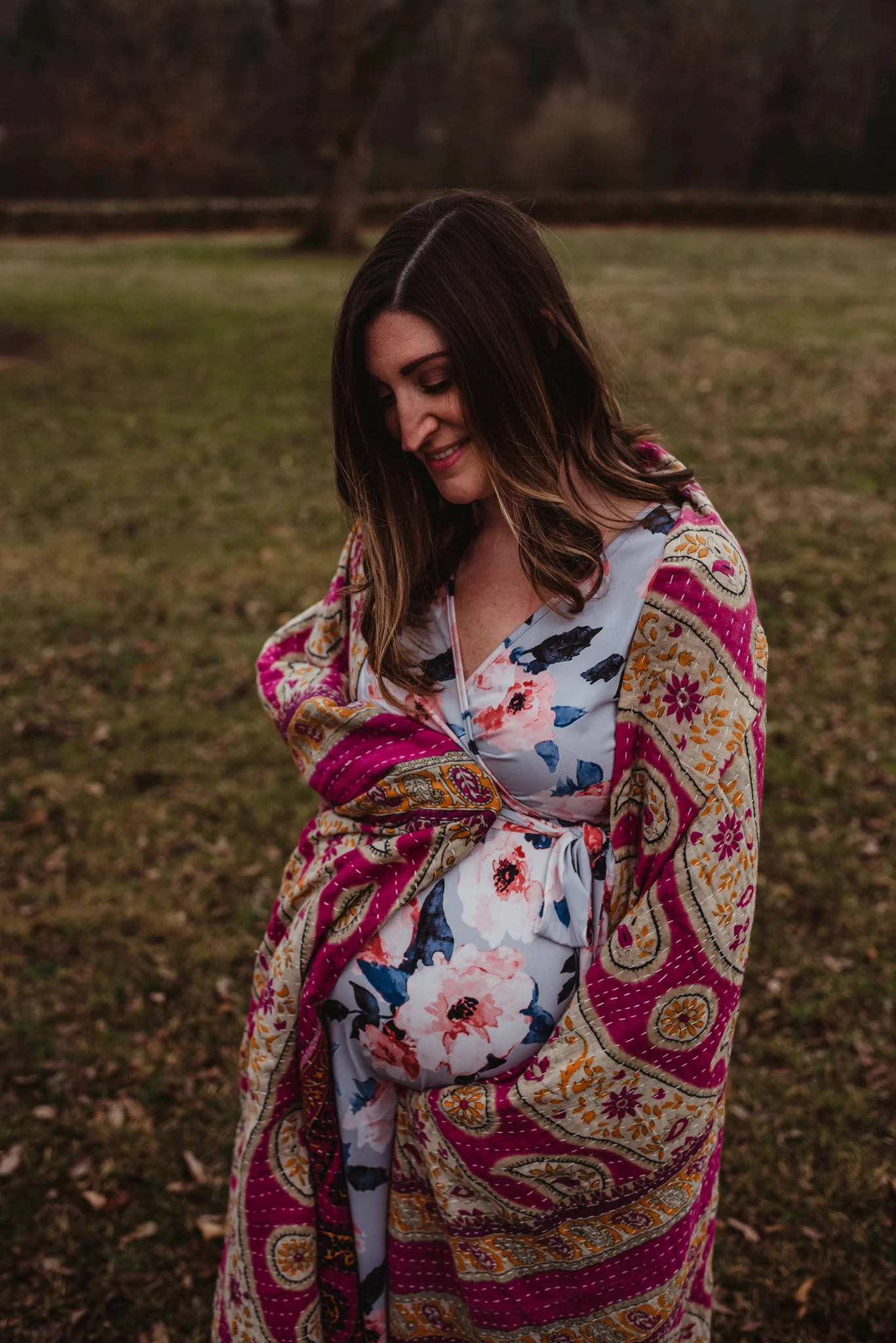 The Mama to be holds her baby bump under a pink blanket, picture taken by Rose Trail Images at Joyner Park in Wake Forest, NC.
