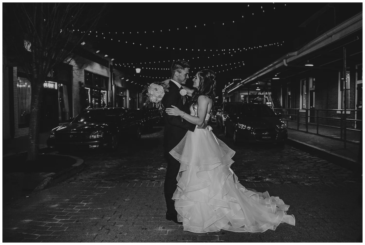 The bride and groom pose for a night portrait at Raleigh’s Market Hall after their wedding ceremony, picture by Rose Trail Images.