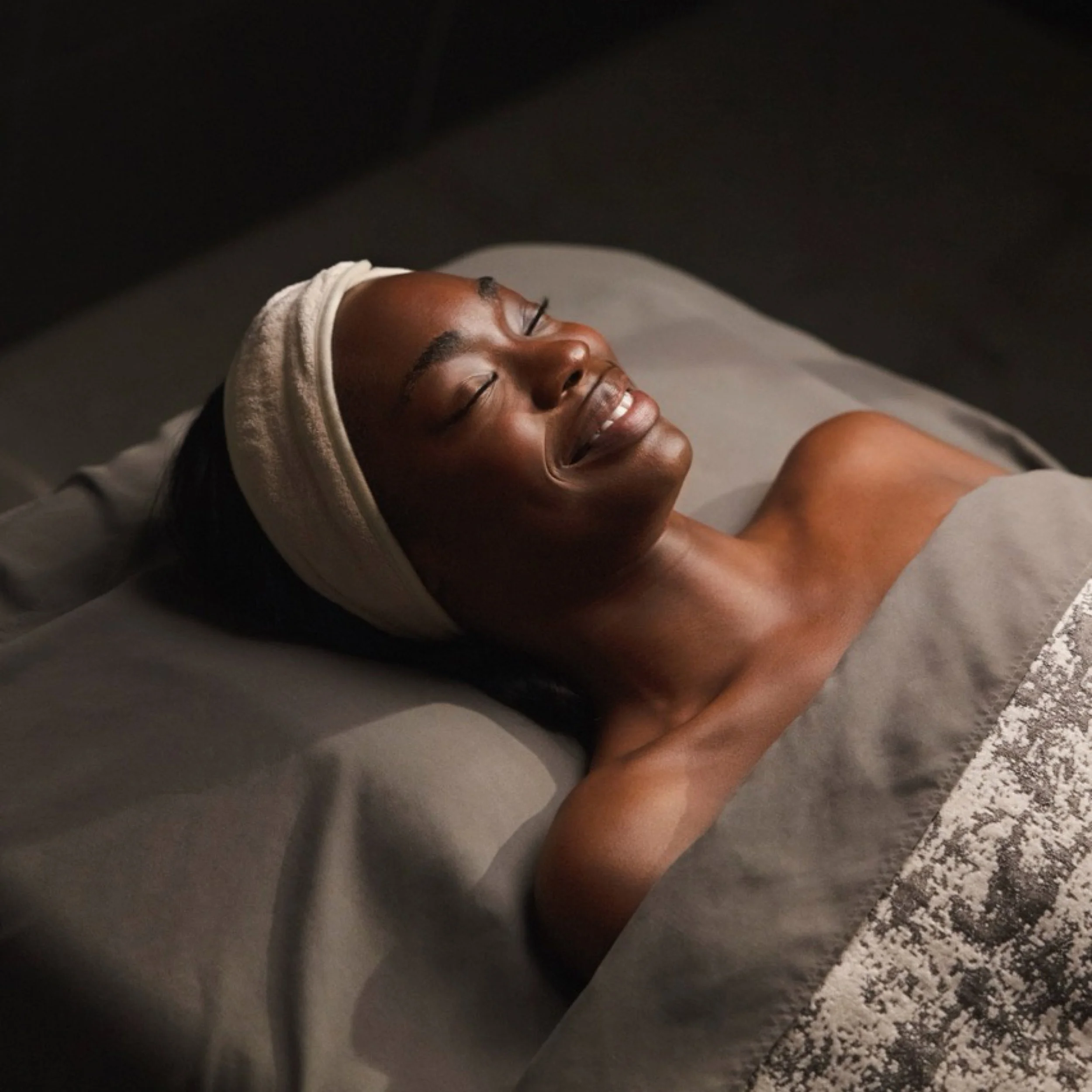 a woman smiling preparing for a spa service
