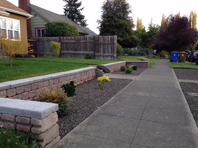 Concrete retaining wall blocks with caps. Front beds are landscaped with crushed gravel.