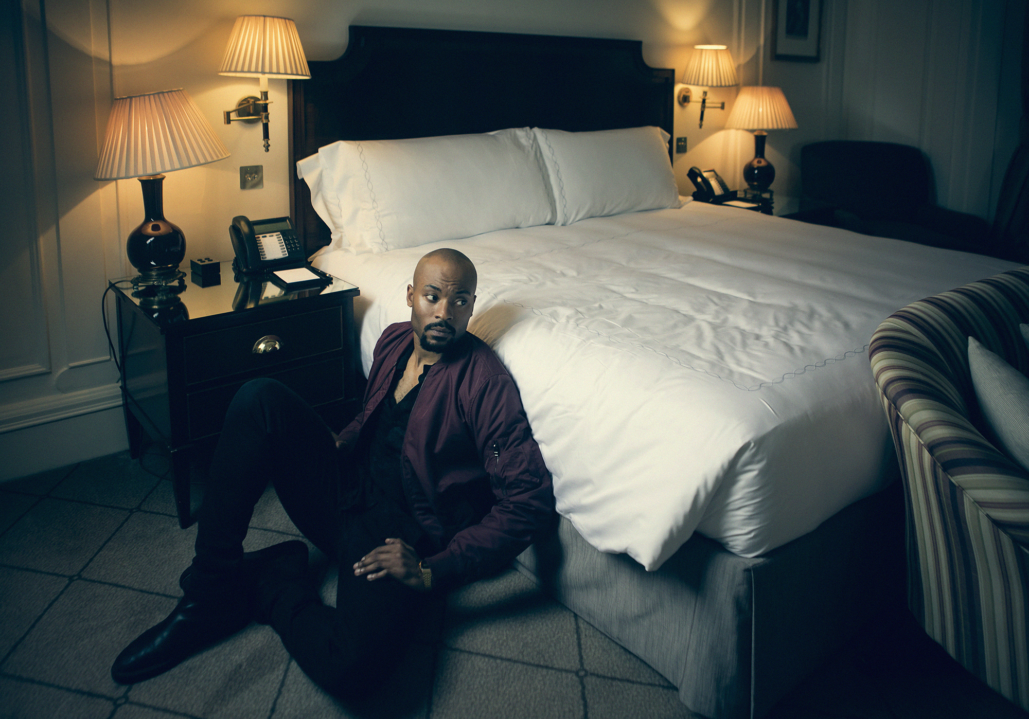 CHOOSING THE SETTING This was the last set up of about 5 that we shot that day. We made use of the lounge area of the hotel suite along with the hall way and the bathroom. I wanted to make use of the glowing bedside lamps in the bedroom and shoot something quite cinematic with Arinze. I could have spent all day/night working on this location. There were so any options to shoot something great and only a small window of time to settle on something. As is the way with almost all shoots! EXPOSURE & LIGHTING For this portrait I needed the most subtle and gentle pop from a strobe. I didn't want to ruin the ambient light by flooding it with light from the flash. I used a Profoto D1 into a 36" Photek Softlighter umbrella with an extra layer of diffusion material to dull it down even further. I positioned the strobe and brolli to camera left so that it was coming from roughly the same angle as the bedside lamp. Here's a shot straight out of camera... Camera : Canon 5d Mk3 ISO : 400 Shutterspeed : 1/125 Aperture : 2.8