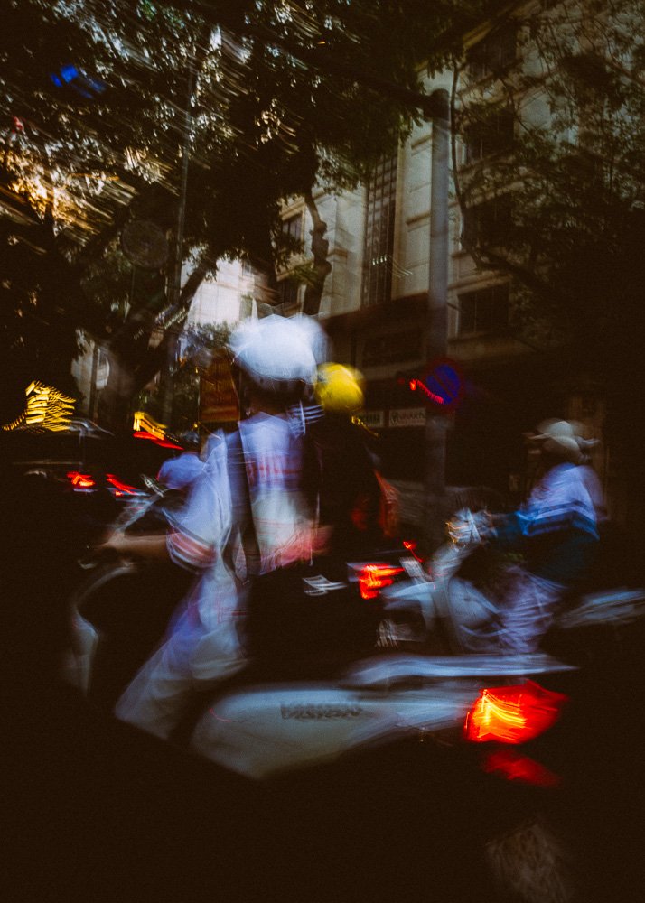 Motorbike riders in helmets blurred in evening traffic