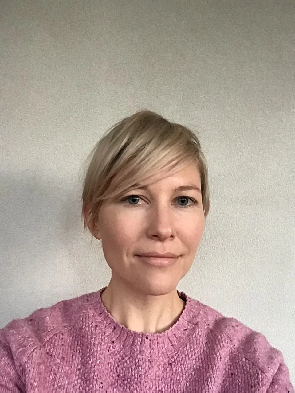 Person wearing pink sweater against light wall