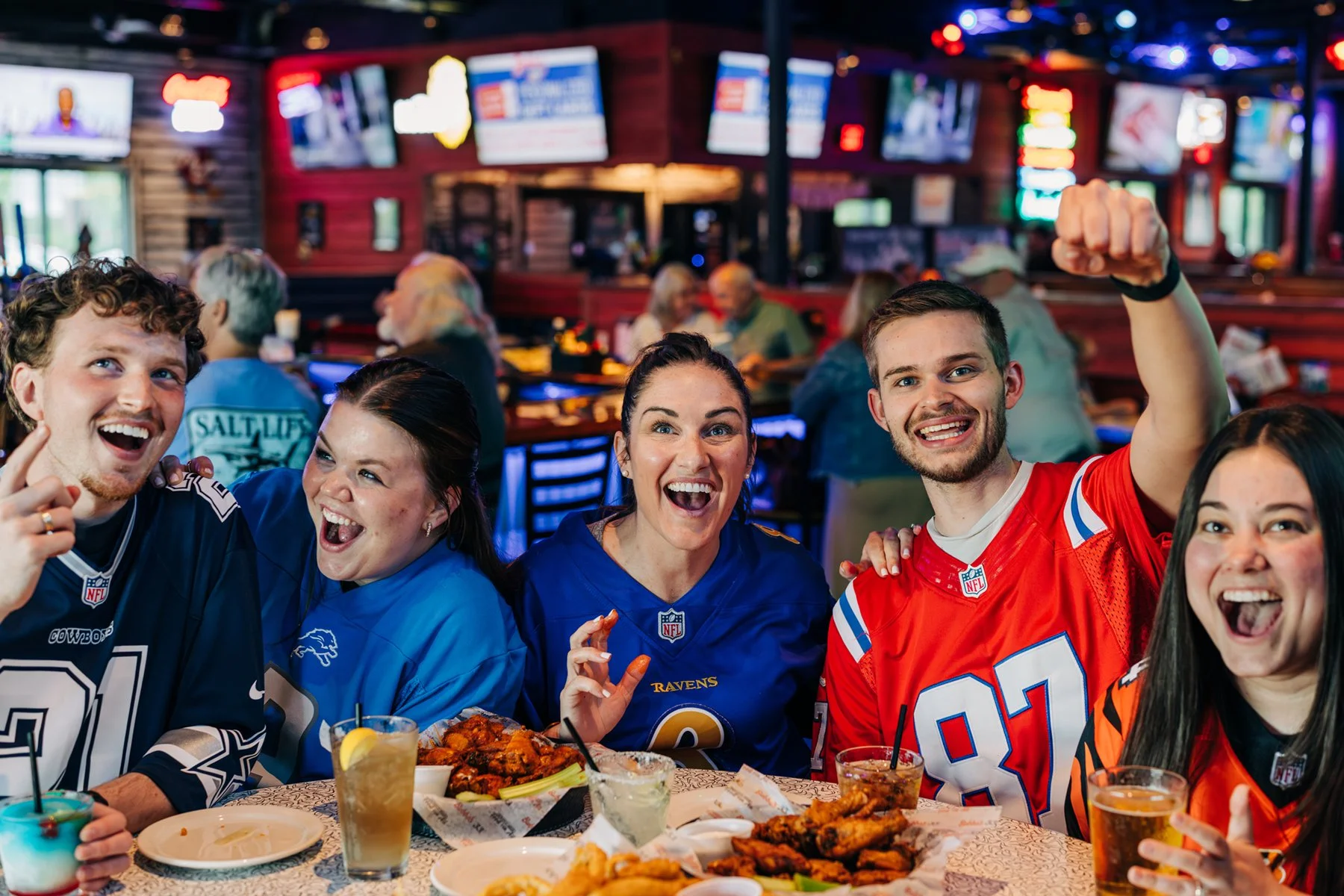  Group of people all wearing football jerseys eating at Bubba’s 33 and watching a football game.  Marking photoshoot in Louisville,KY  