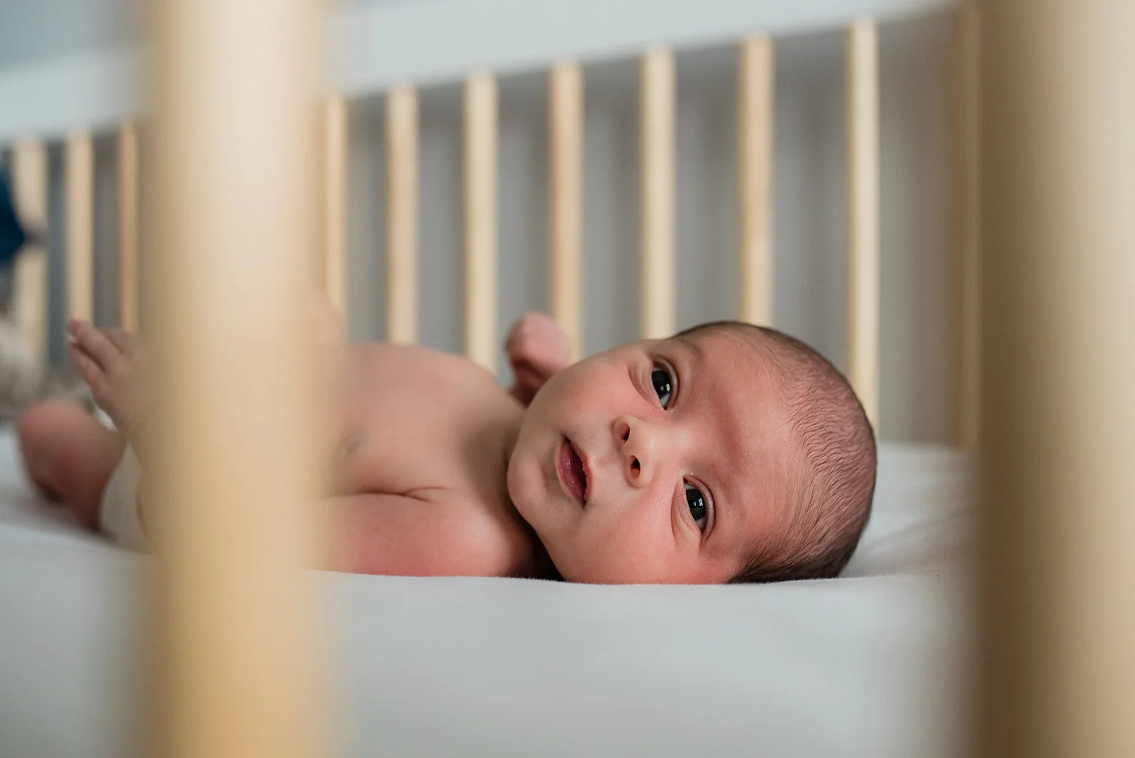 Baby staring sleepily out of the crib, Newborn Photography Annapolis, Penny Lane Lifestyle Photography
