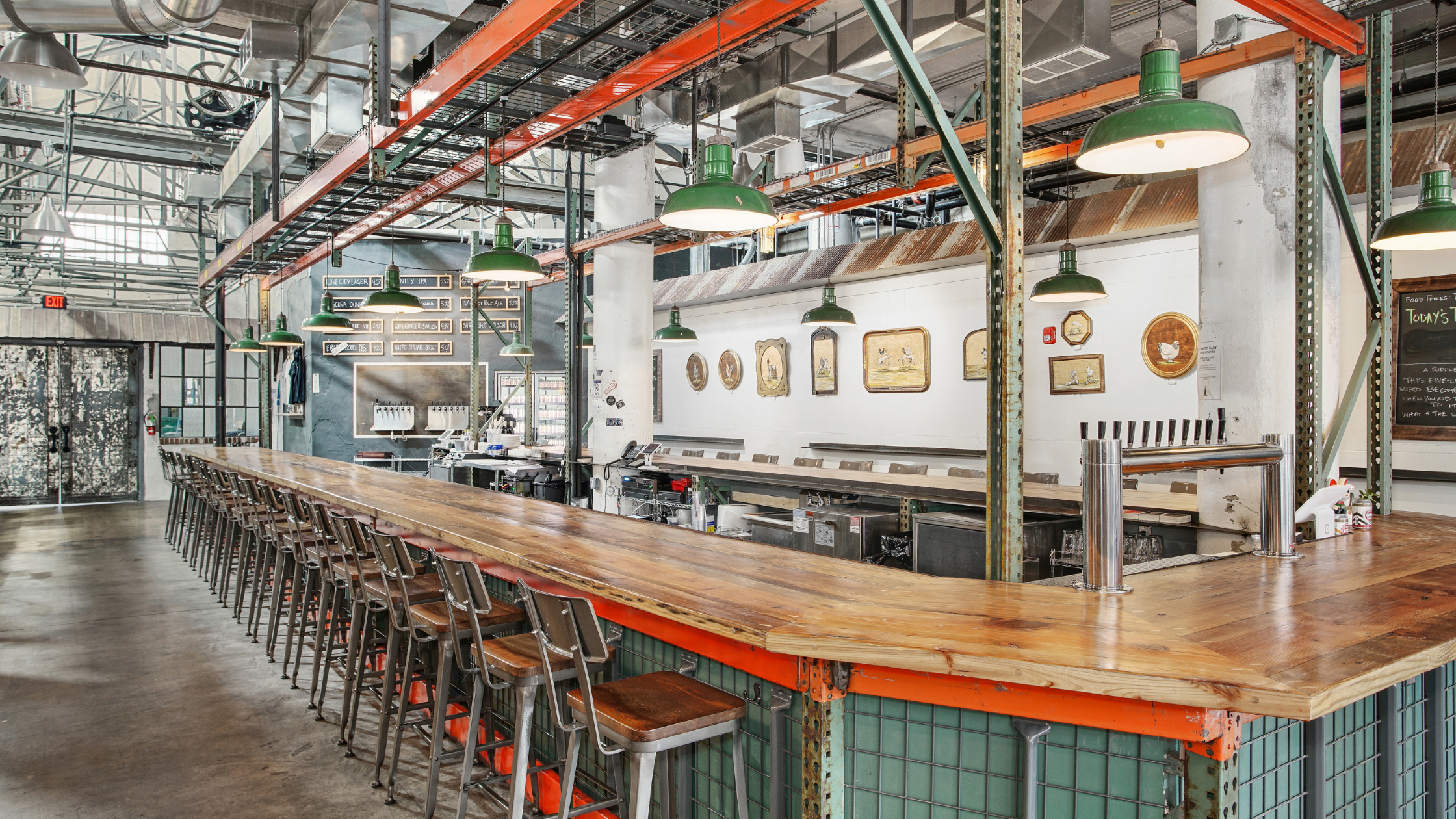  The Taproom at Love City Brewing features a large scale central U-shaped bar with industrial details.  