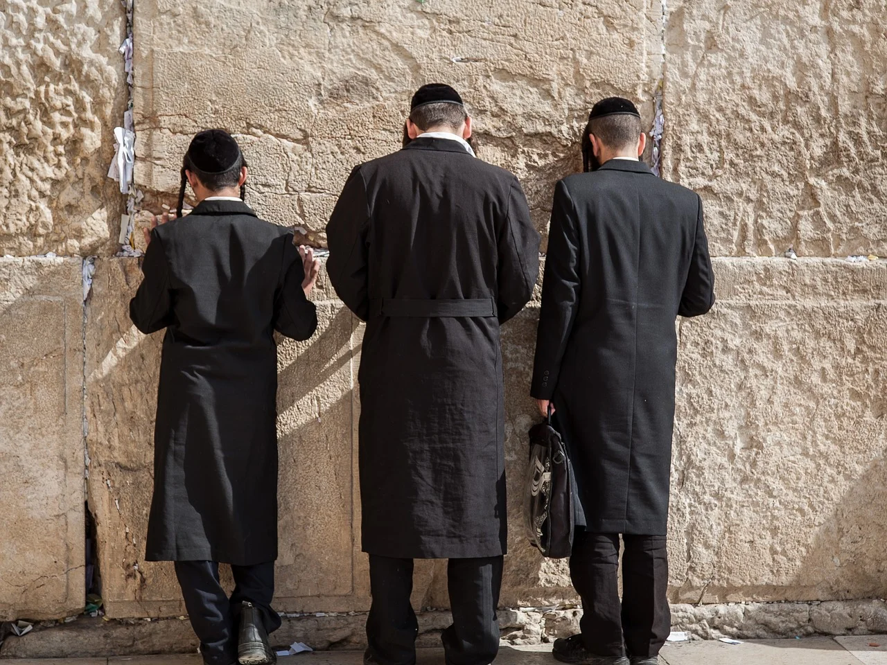 Three Jewish men pray at the Western Wall in Jerusalem. Creative Commons.